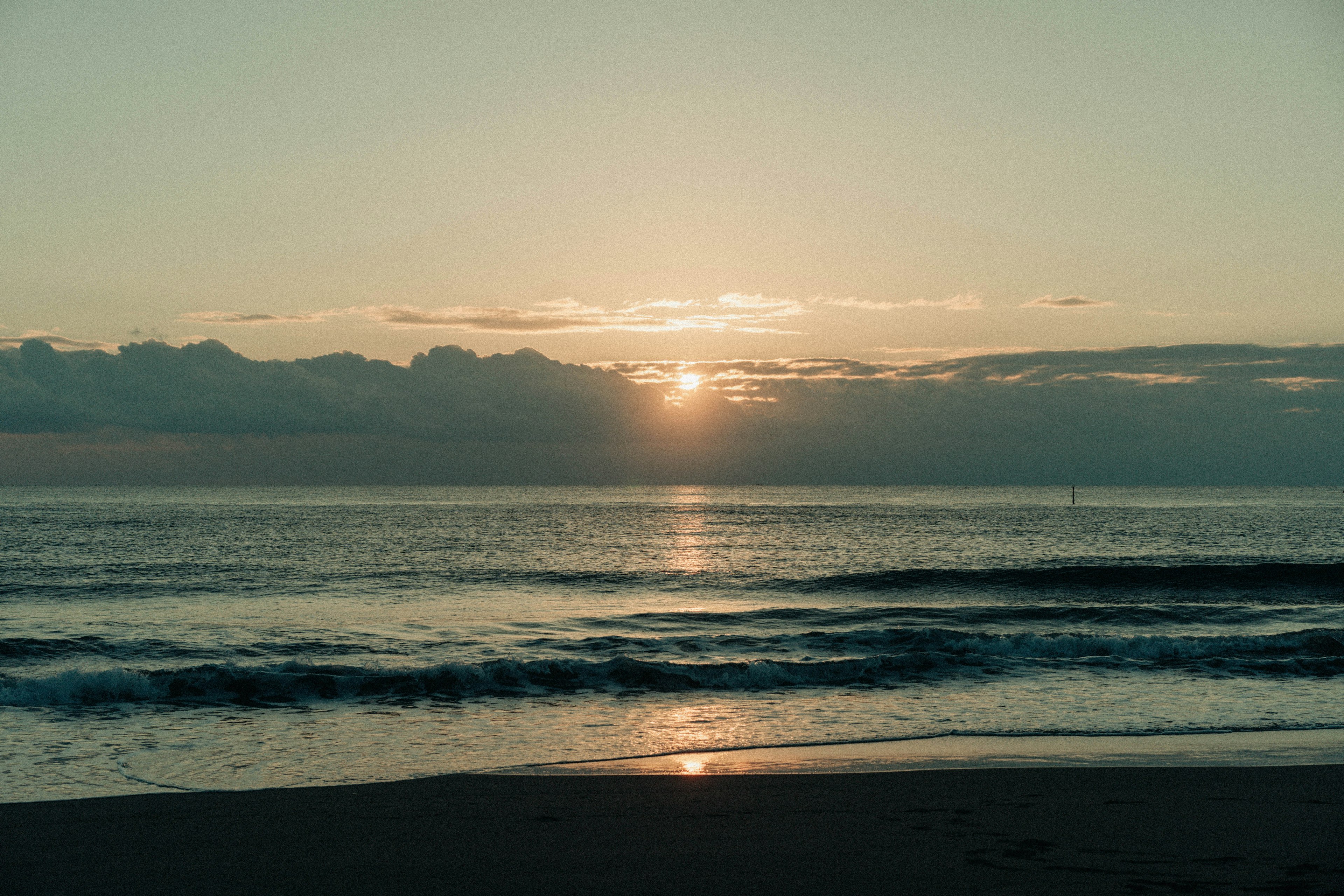 Tranquil beach scene with sunset over the horizon