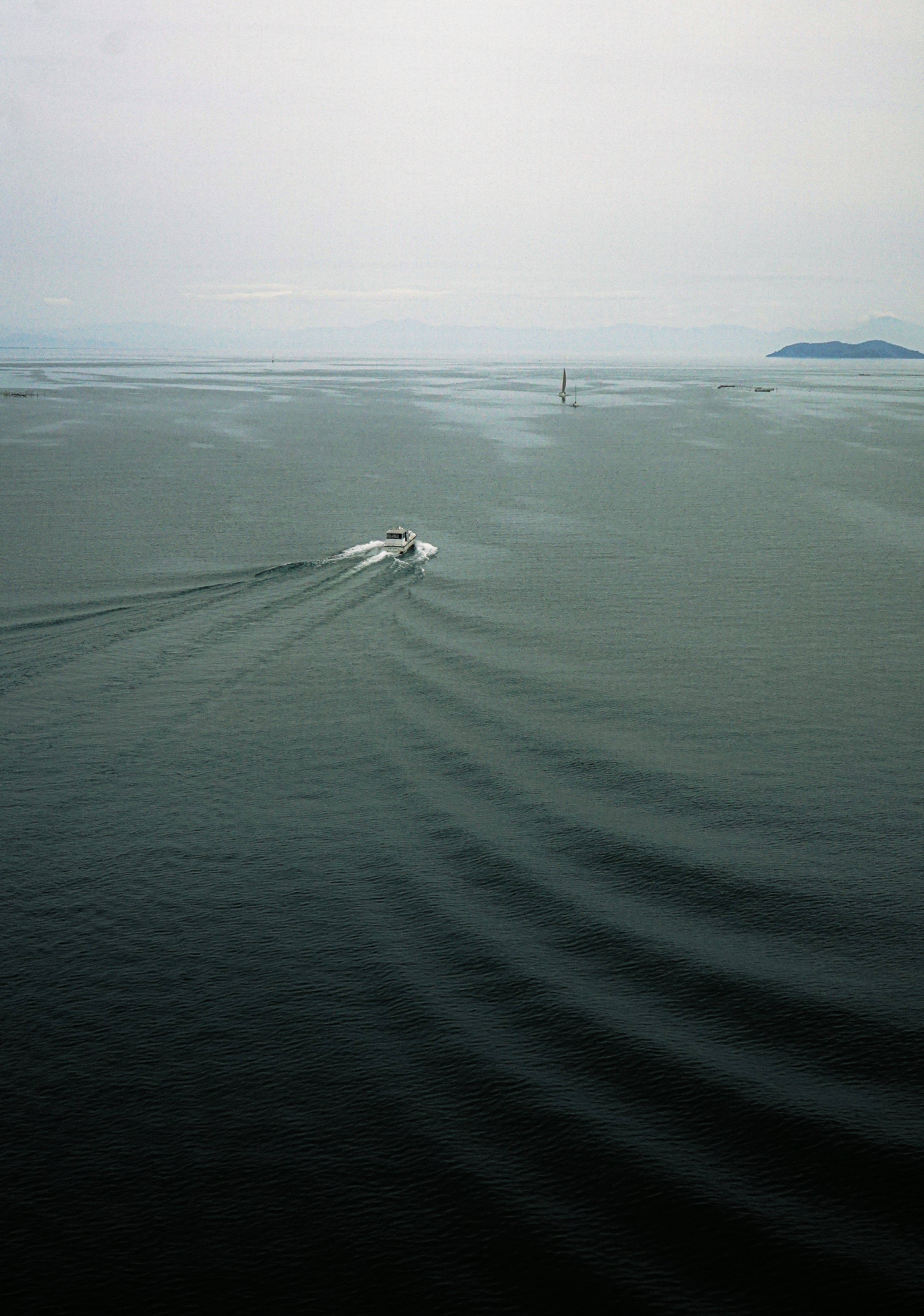 静かな海の上を進むボートの後ろに波紋が広がる景色