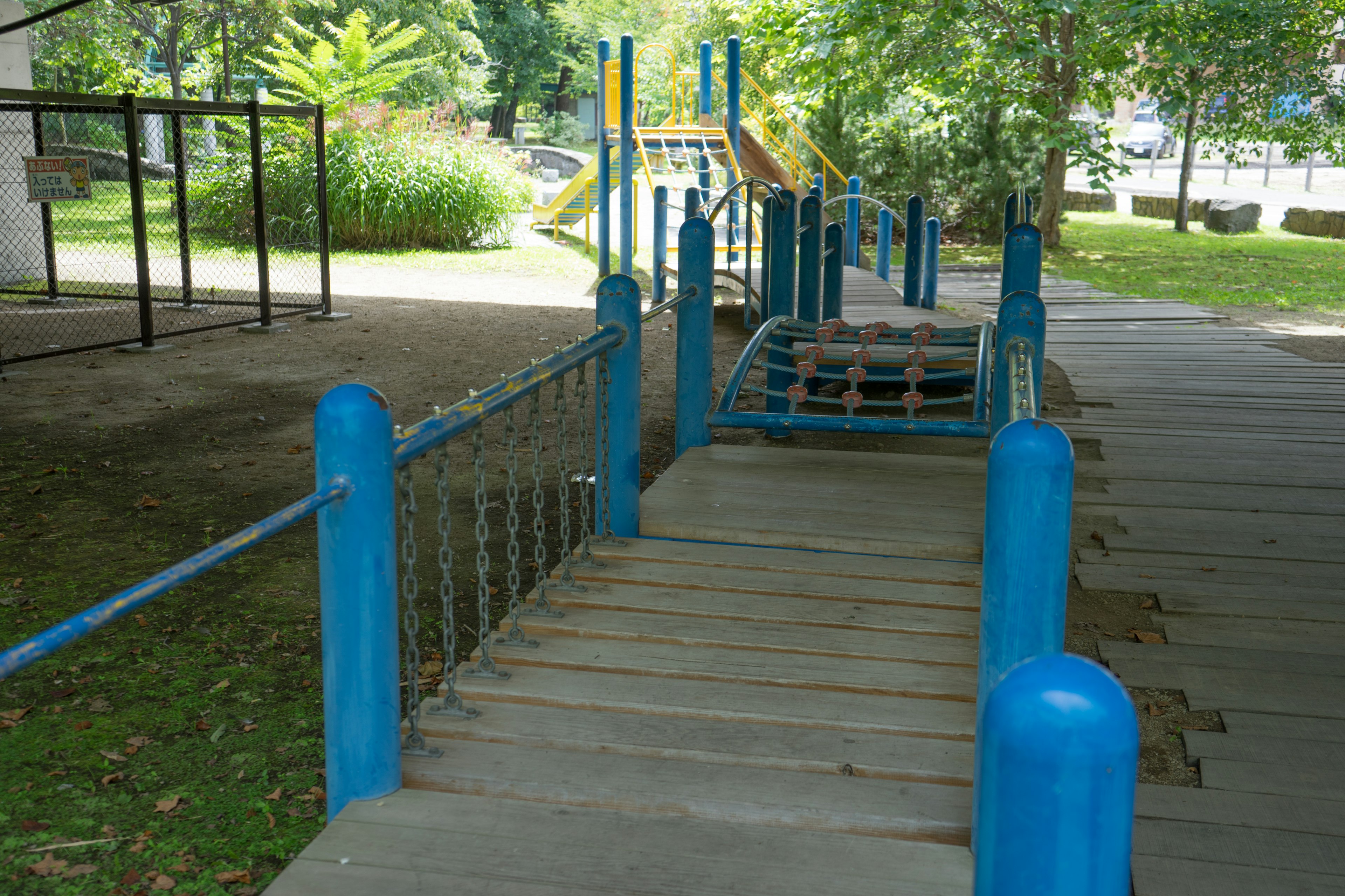 Jembatan taman bermain dengan pegangan biru dan lantai kayu