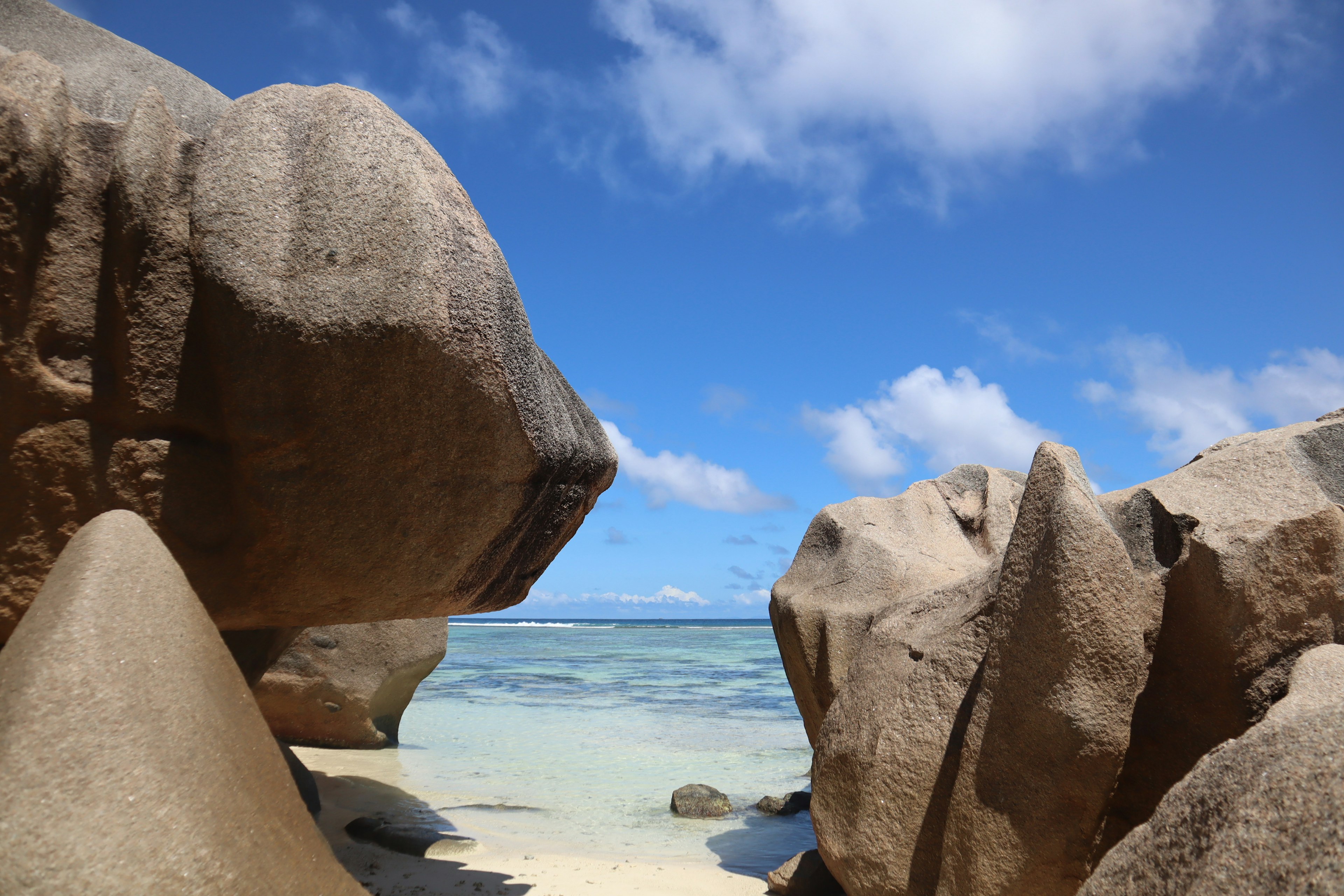 Beach landscape featuring large rocks surrounded by blue sky and sea