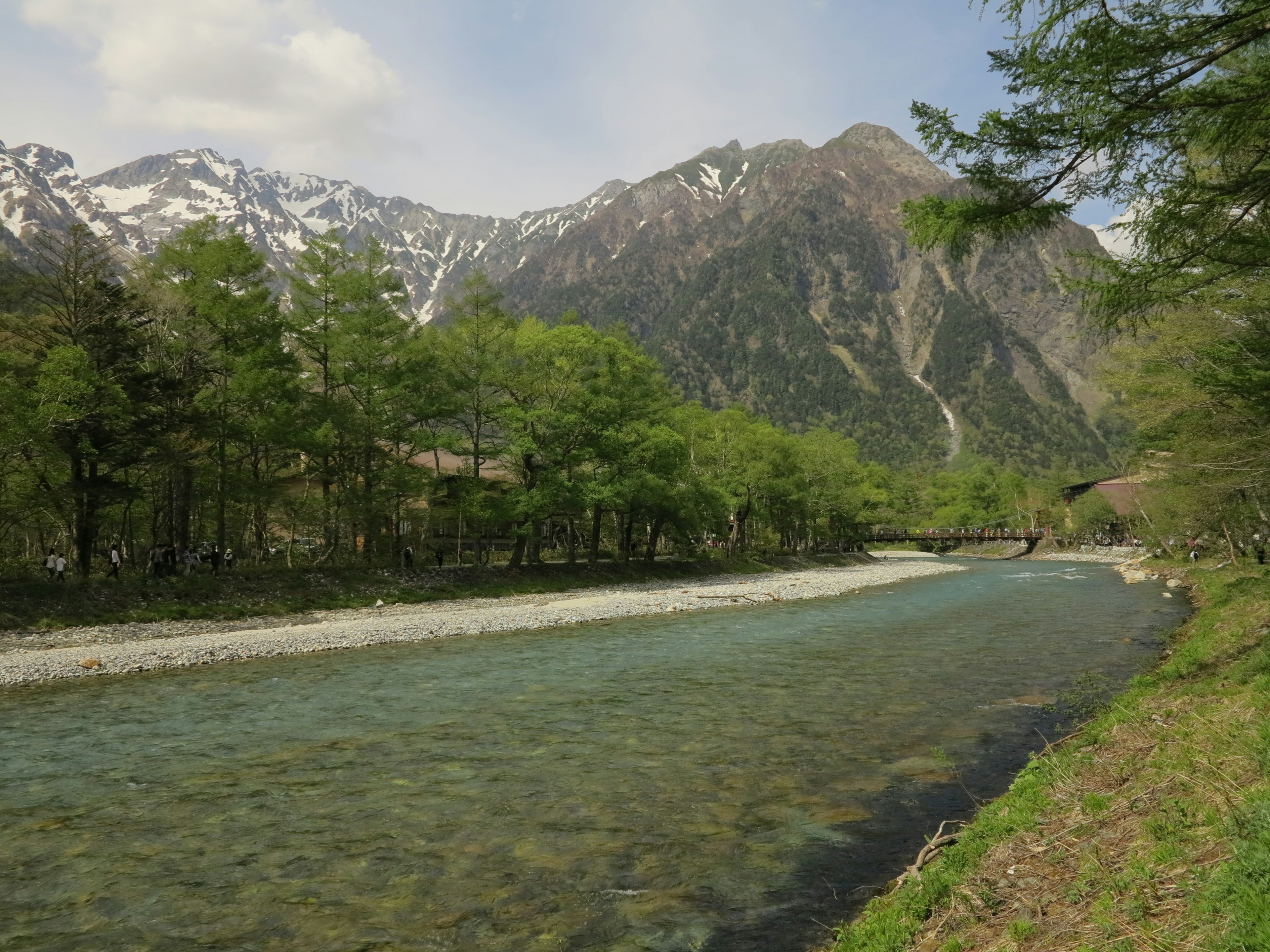 Pemandangan indah dengan gunung dan sungai jernih pohon hijau dan puncak bersalju