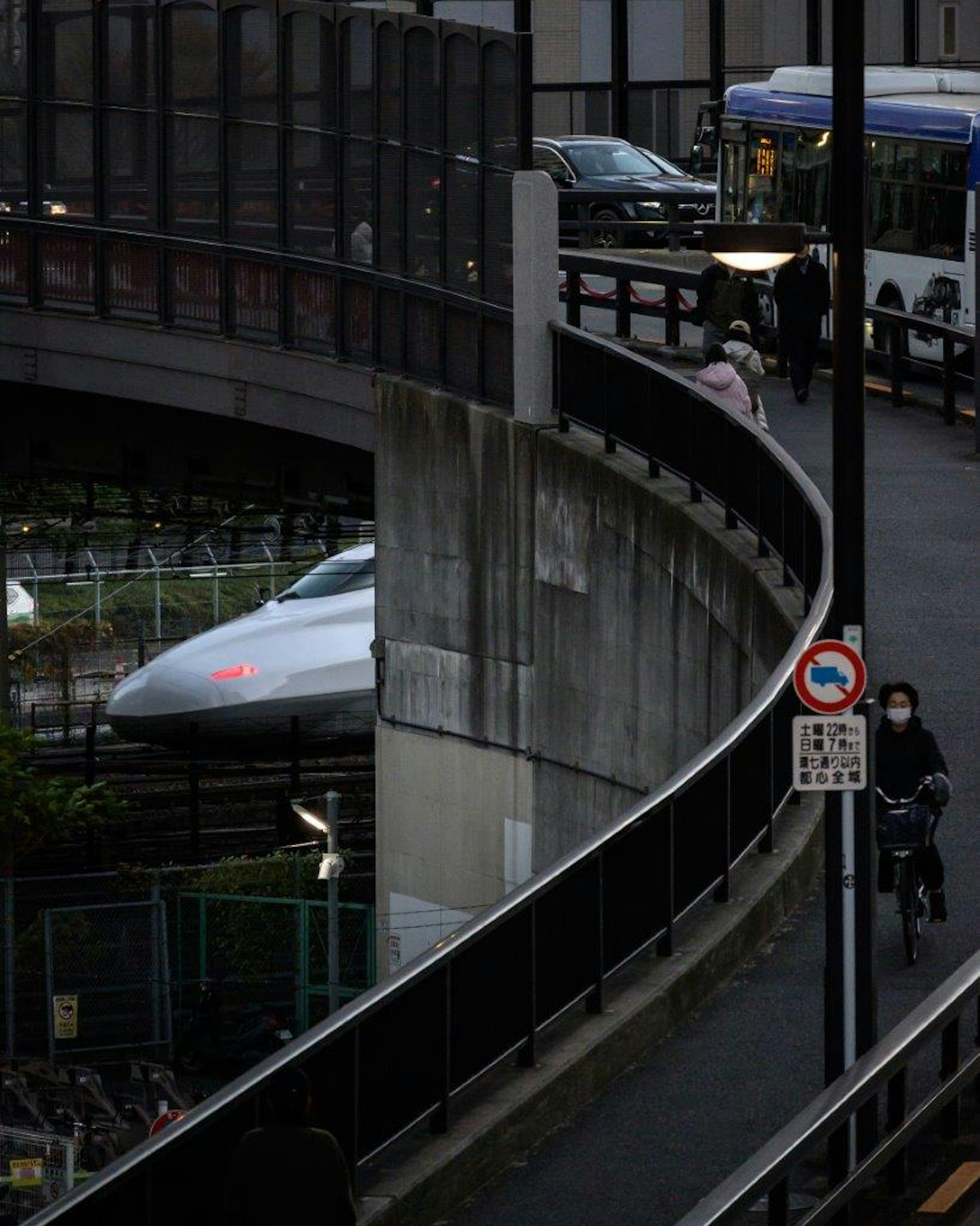 曲がりくねった道路に沿って進む自転車とバスの風景 新幹線の一部が見える