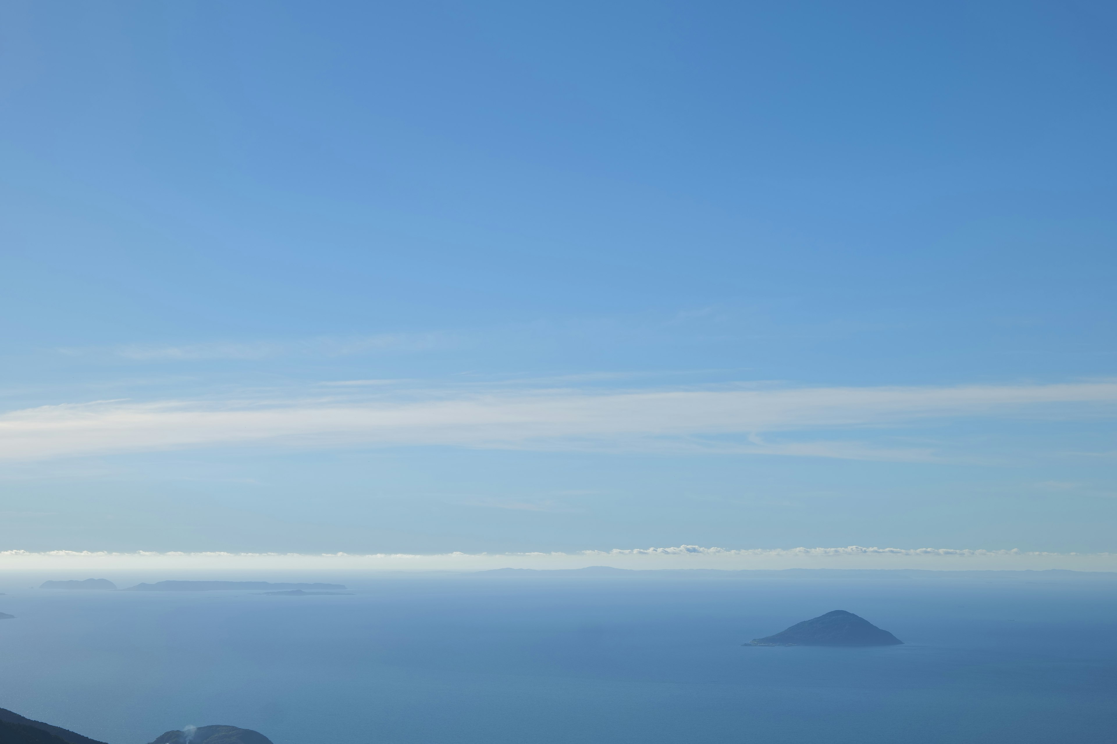 Eine Landschaft mit einer kleinen Insel im blauen Meer unter einem klaren Himmel