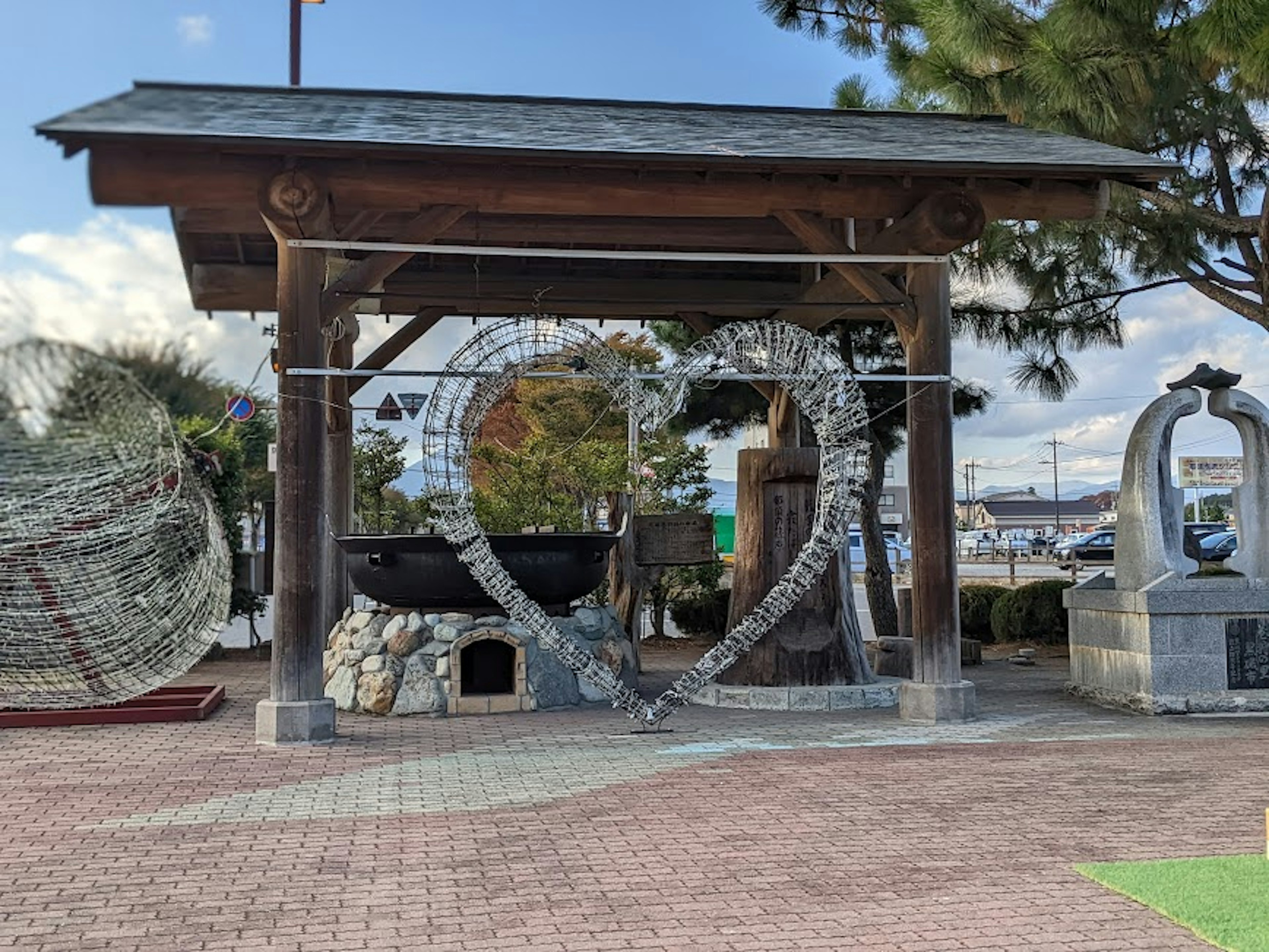 木製の屋根の下に大きなハート形のアートと石の彫刻がある公園の風景