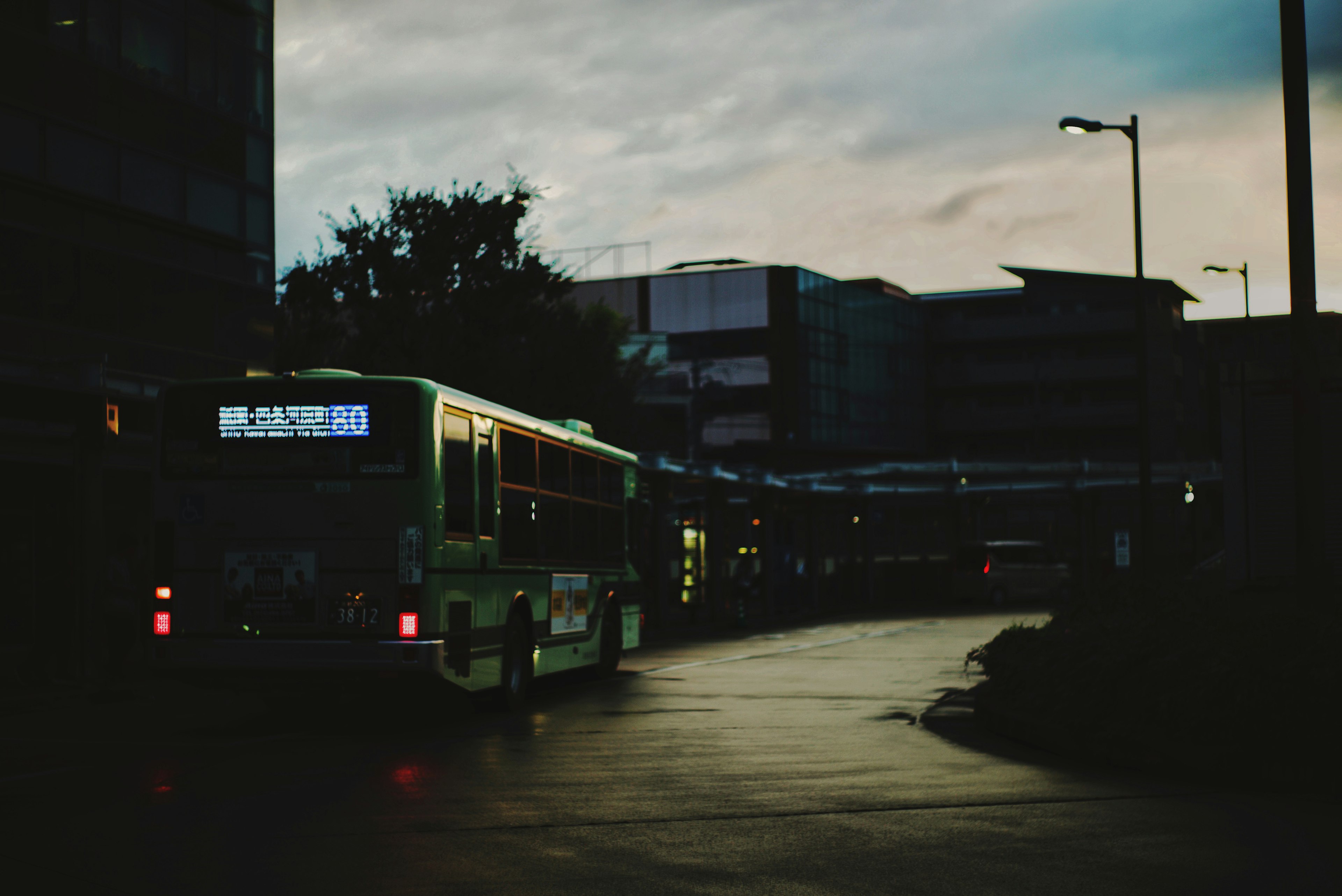 Bus navigating a dimly lit urban street at dusk