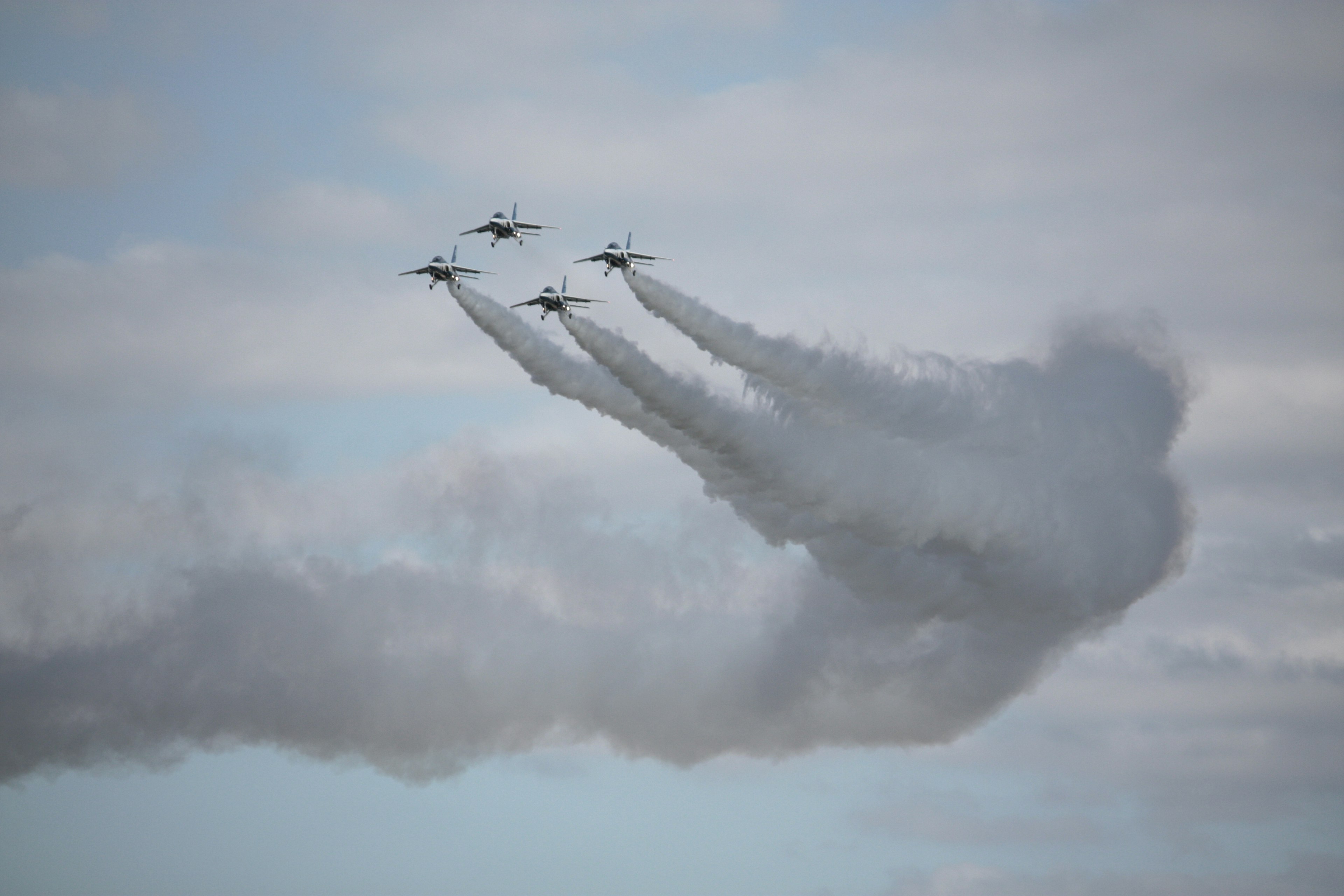 4機の戦闘機が煙を引きながら飛行するシーン