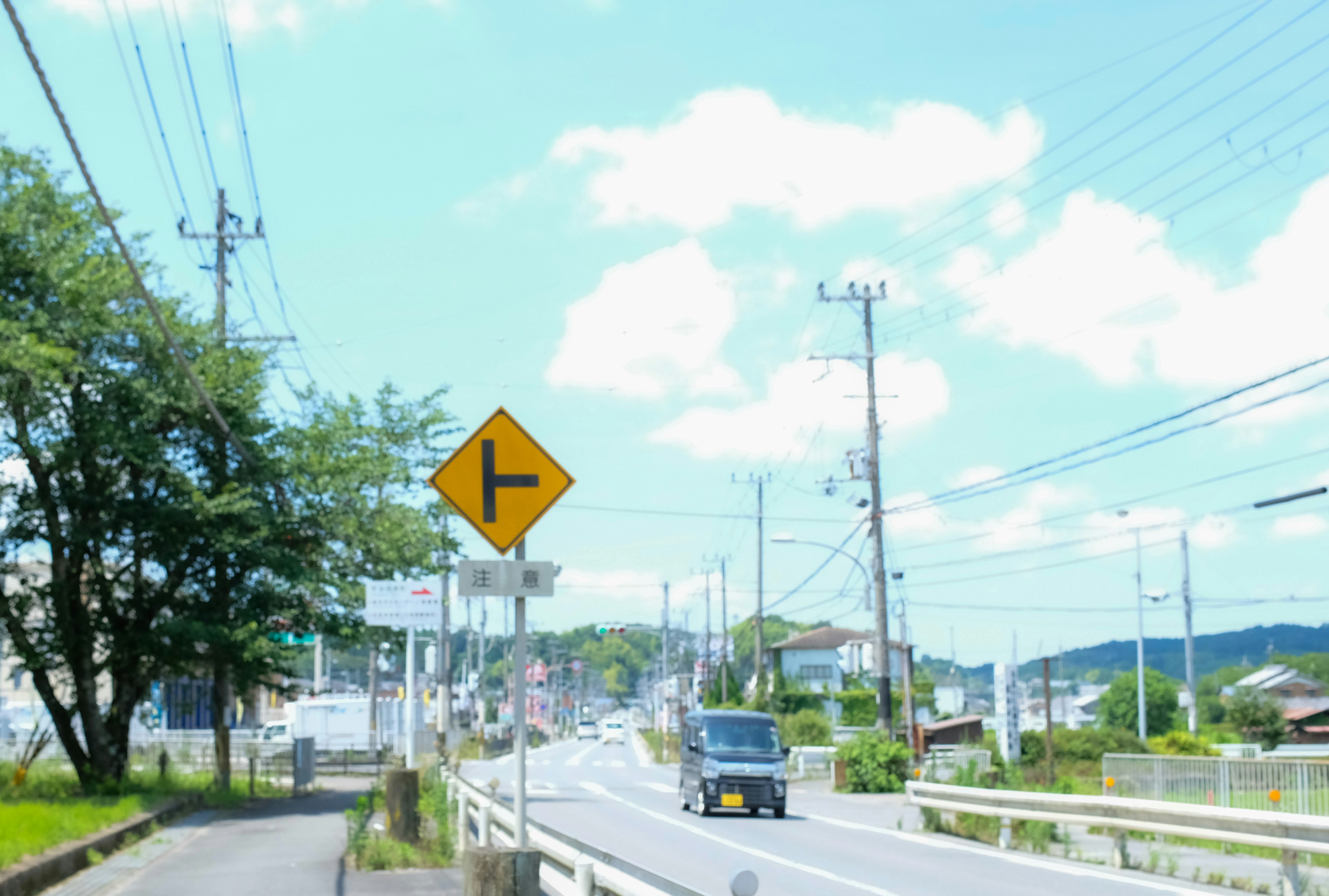 青空と白い雲の下で左折の標識がある道路の風景