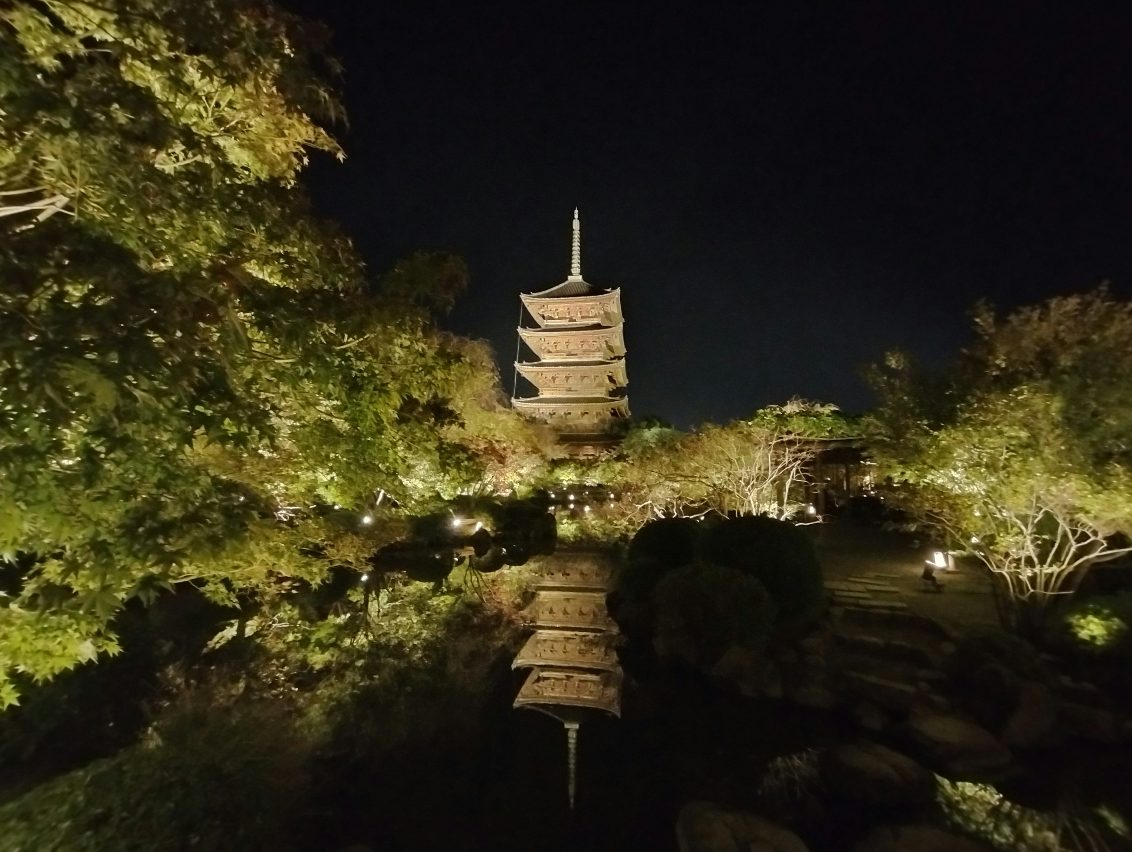 夜间照亮的塔在宁静的日本花园中反射