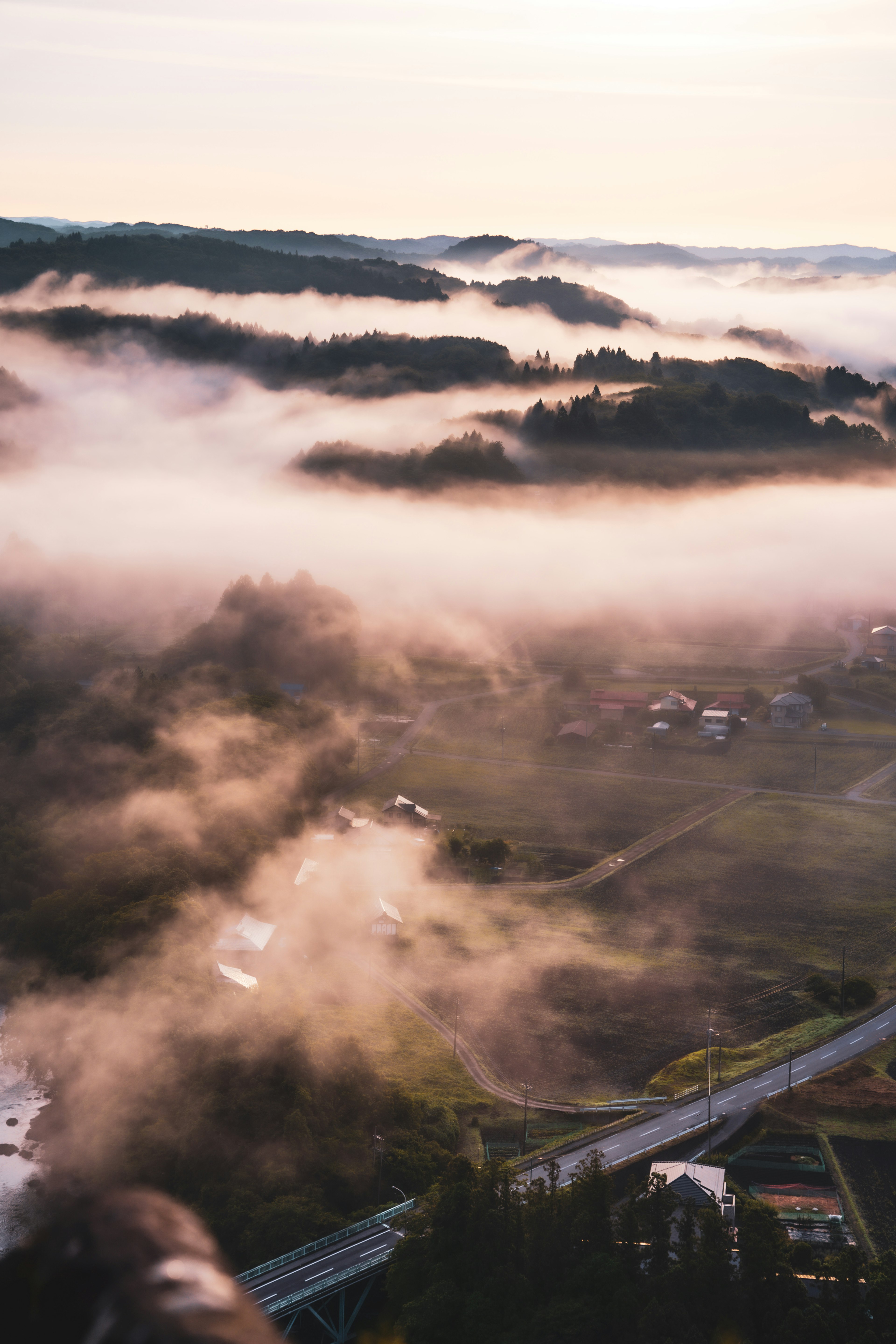 霧に包まれた山々と谷の景色 遠くに見える住宅と道路