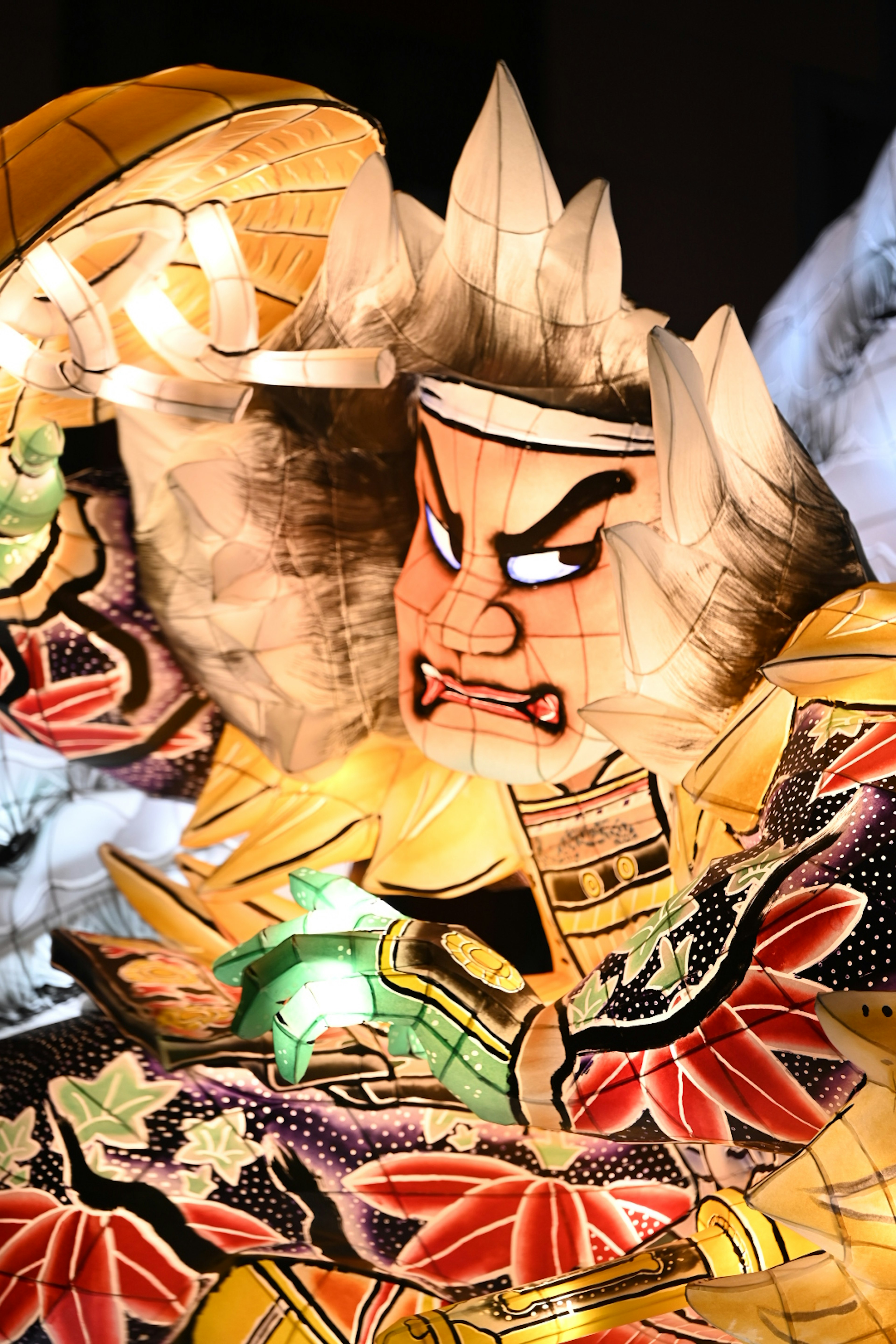 A colorful lantern-like character made of washi paper with an angry expression holding something in its hand