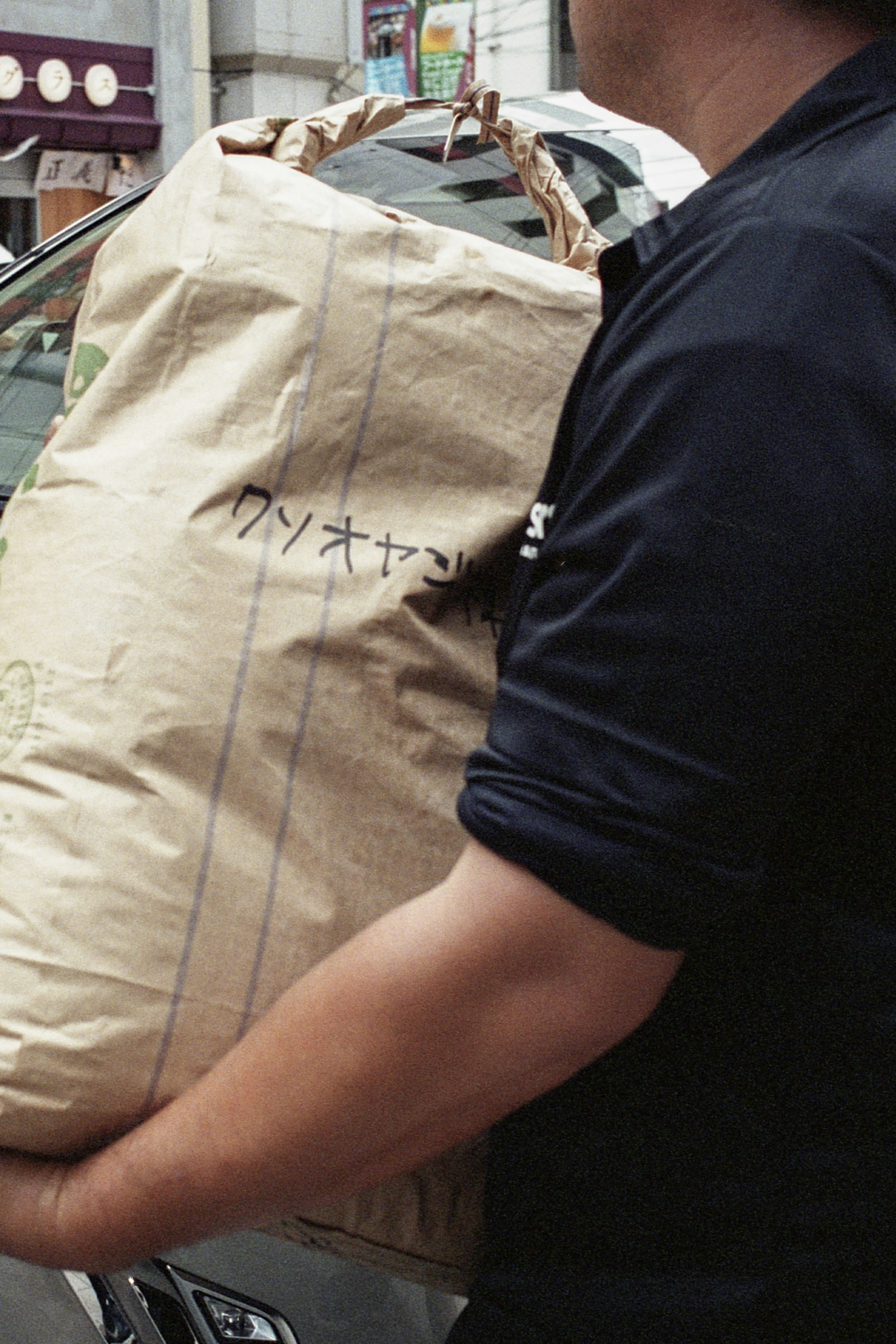 Ein Mann trägt ein großes Paket, das in braunes Papier gewickelt ist