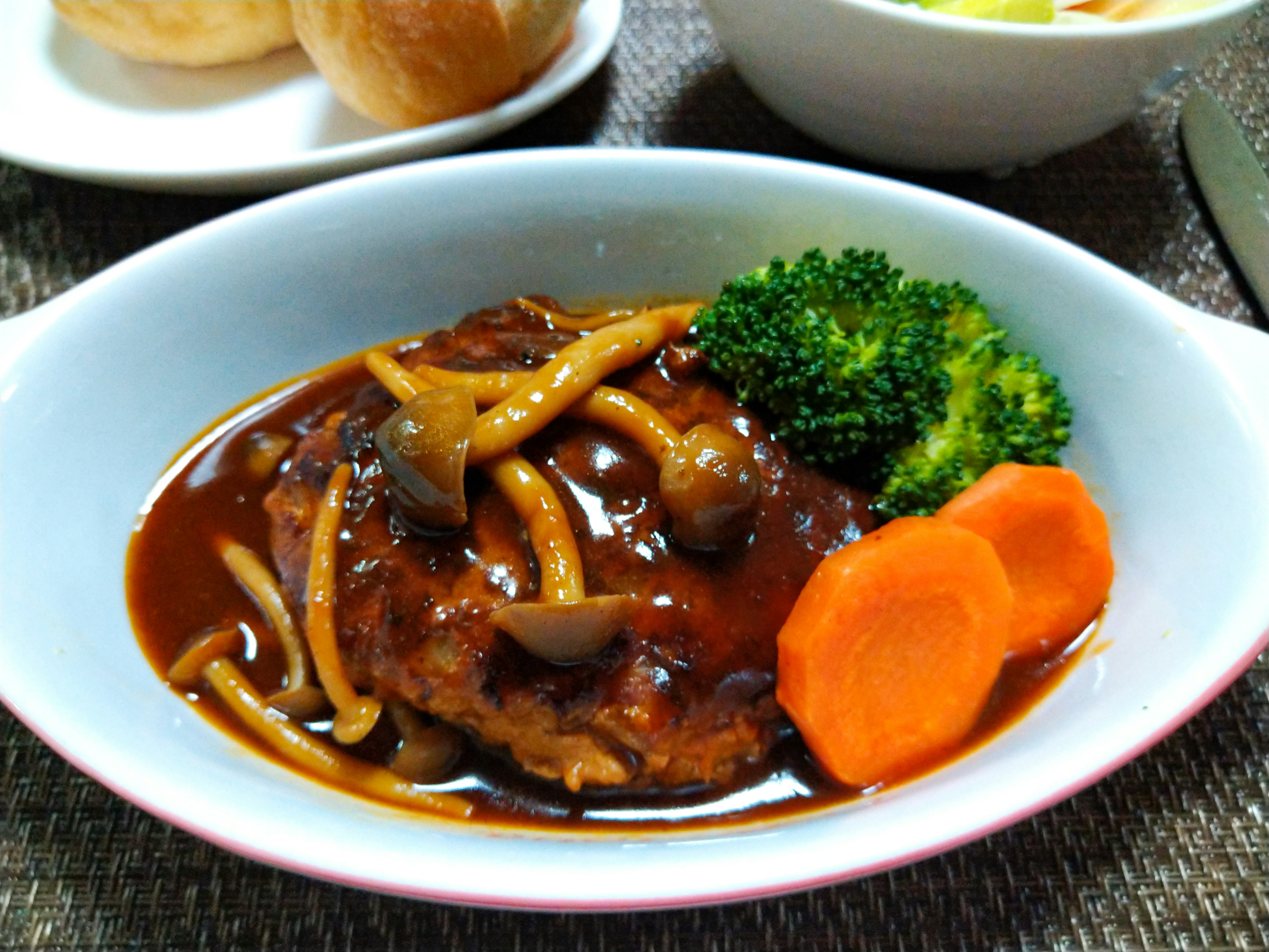 Hidangan yang menampilkan steak hamburger dengan saus teriyaki disajikan dengan brokoli dan wortel