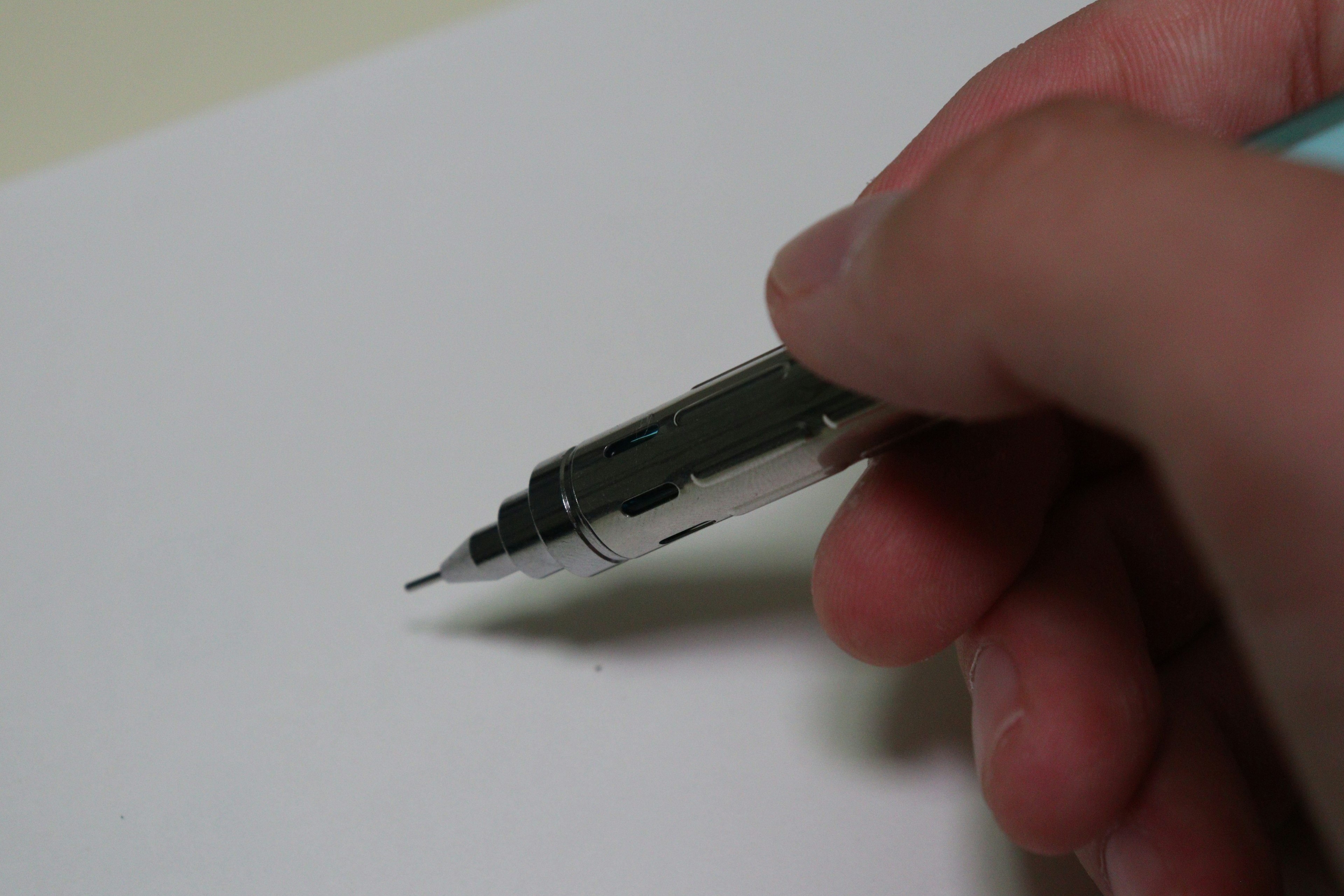 A hand holding a pen poised over a blank sheet of paper