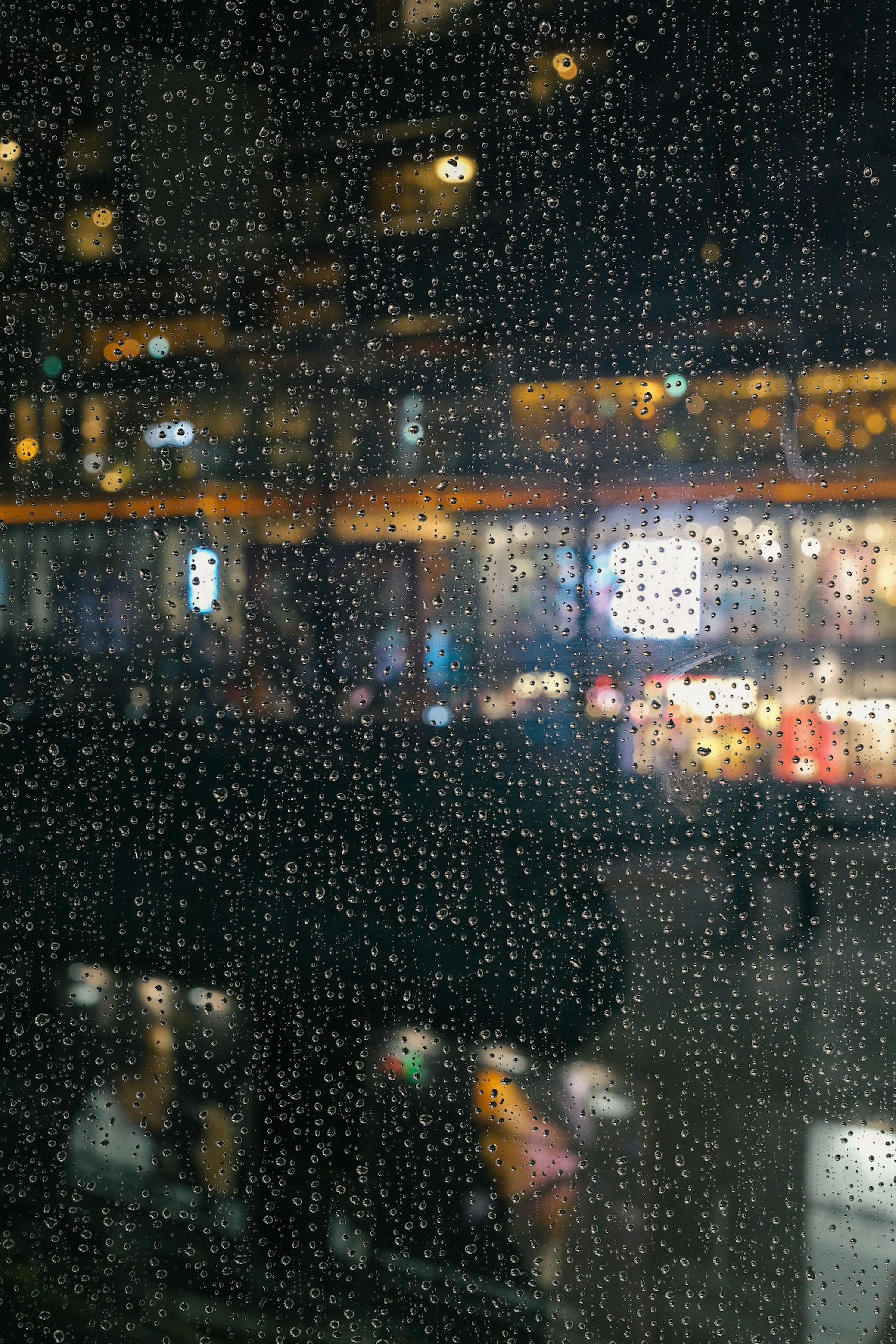 City view through a rain-drenched window with blurred lights