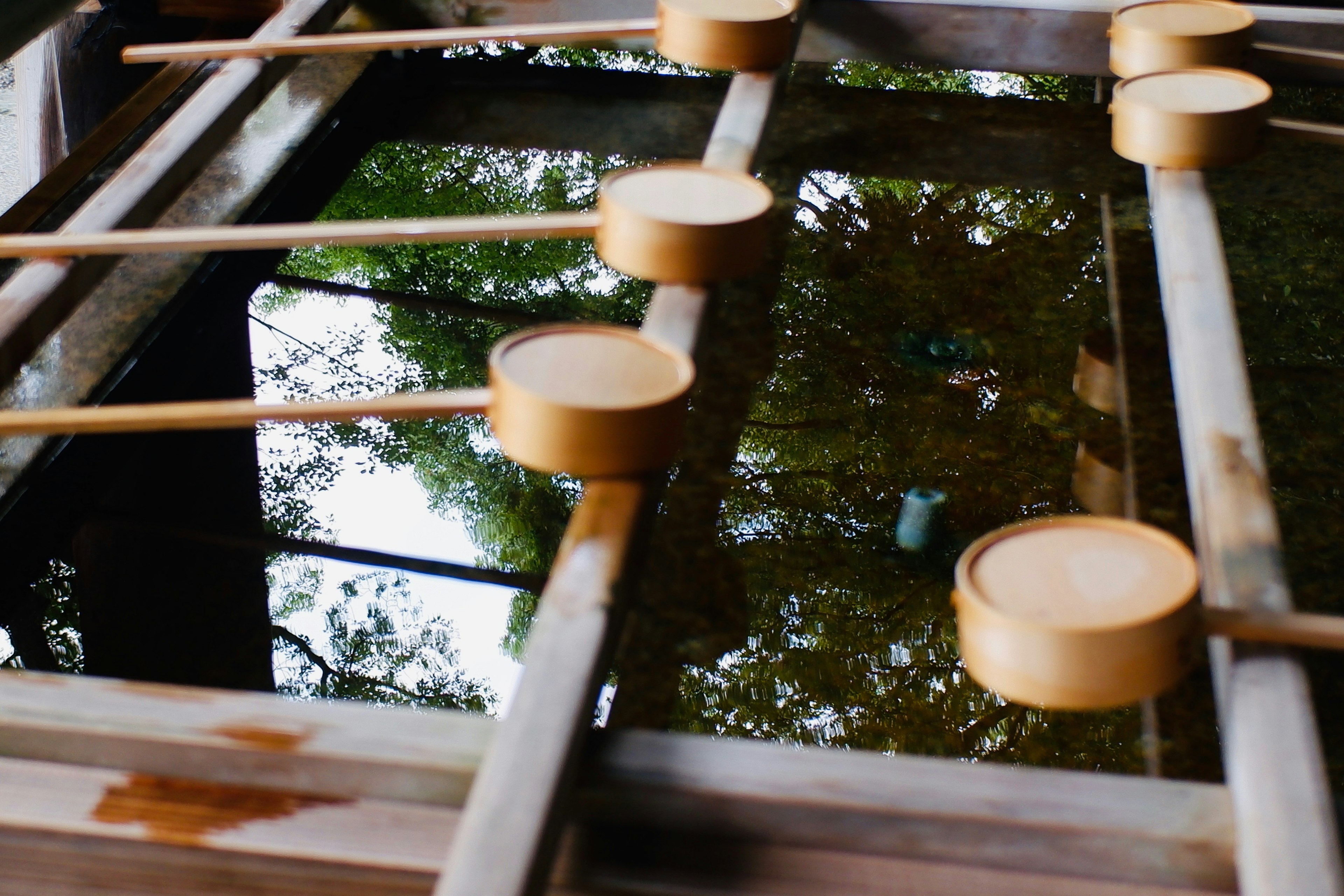 Holzlöffel und Bambusstruktur, die sich auf der Wasseroberfläche spiegeln