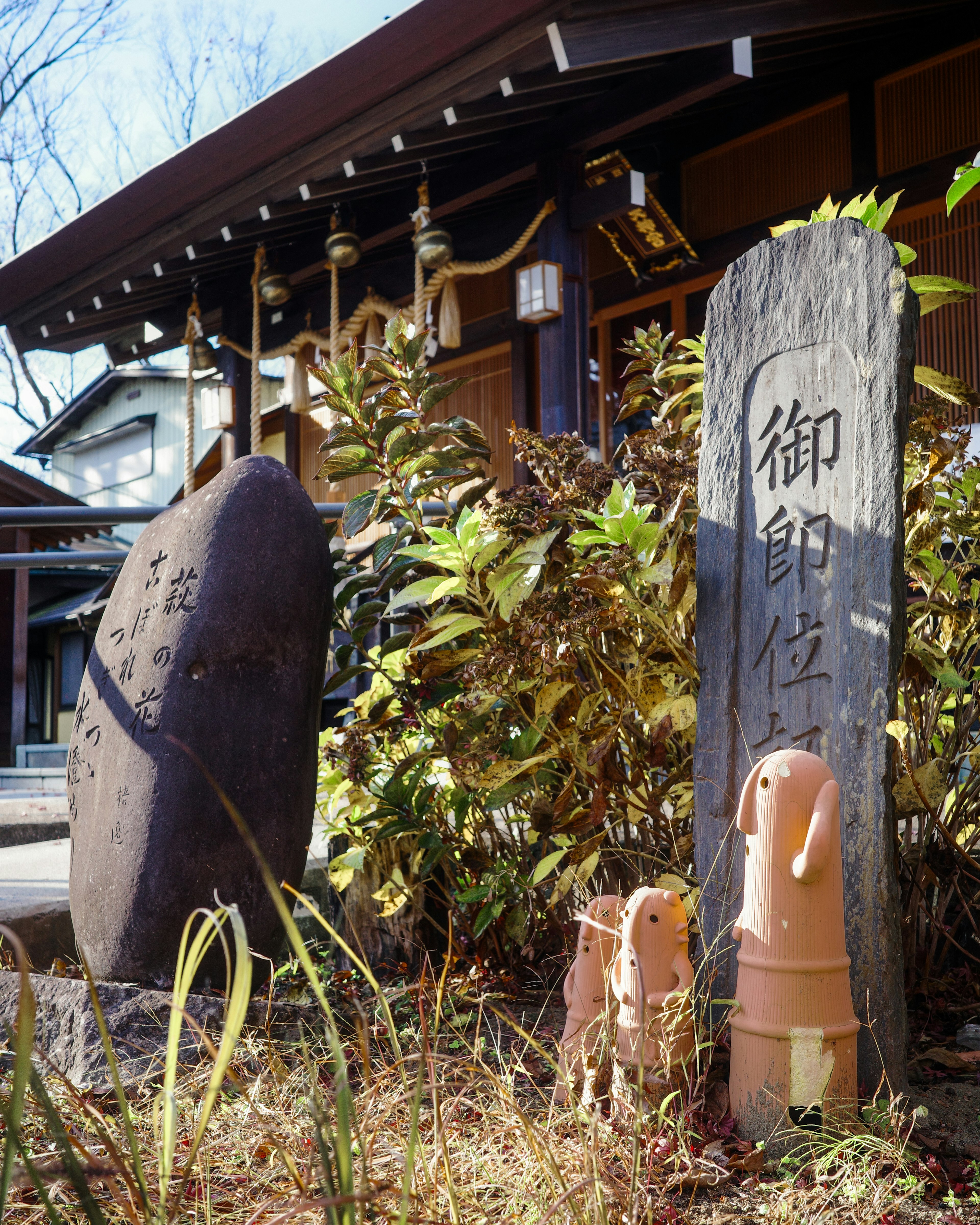 石碑と陶器の小像が見える日本の風景