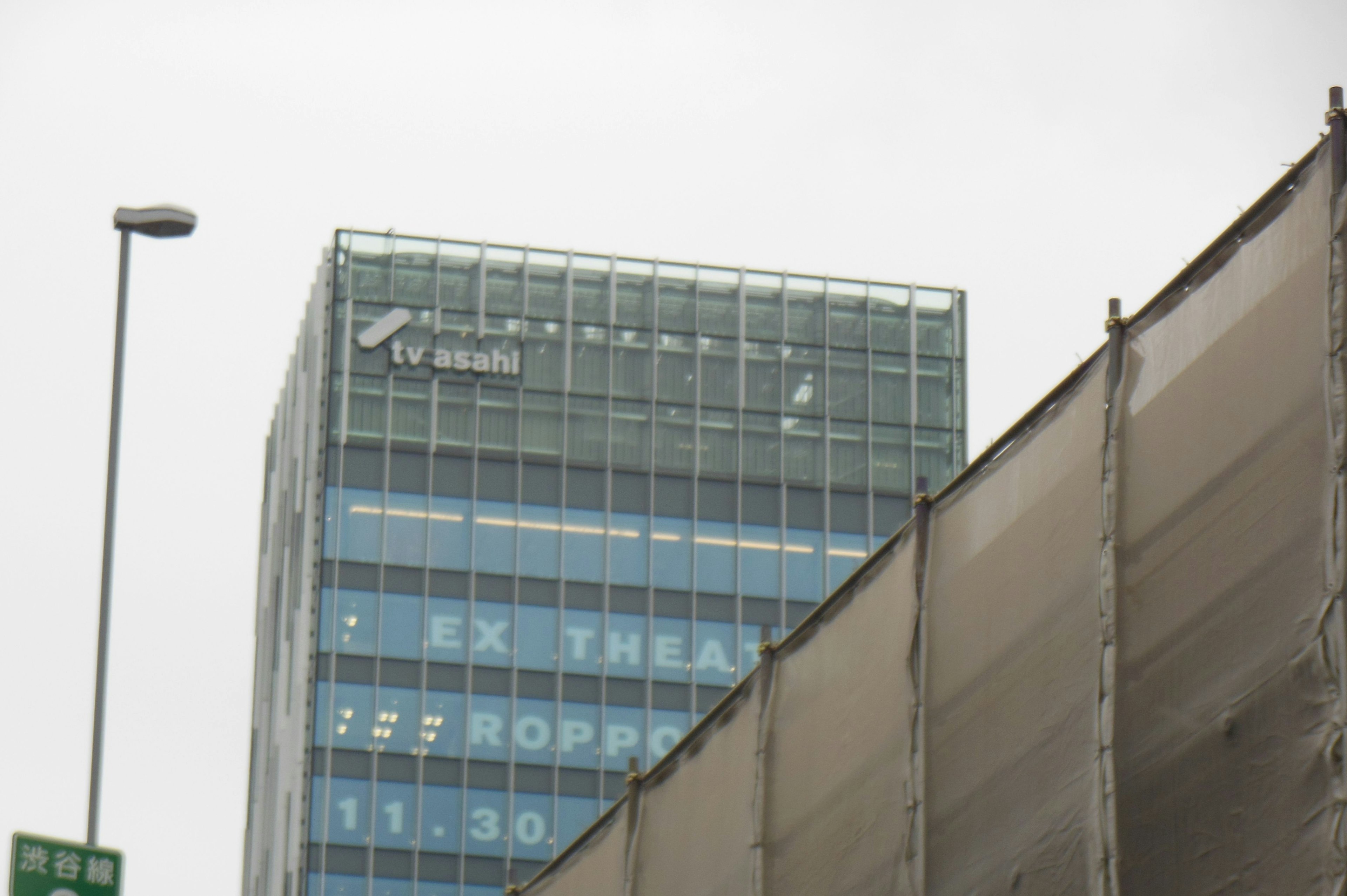 Immagine di un edificio moderno con facciata in vetro Logo della stazione TV visibile in cima sotto un cielo nuvoloso