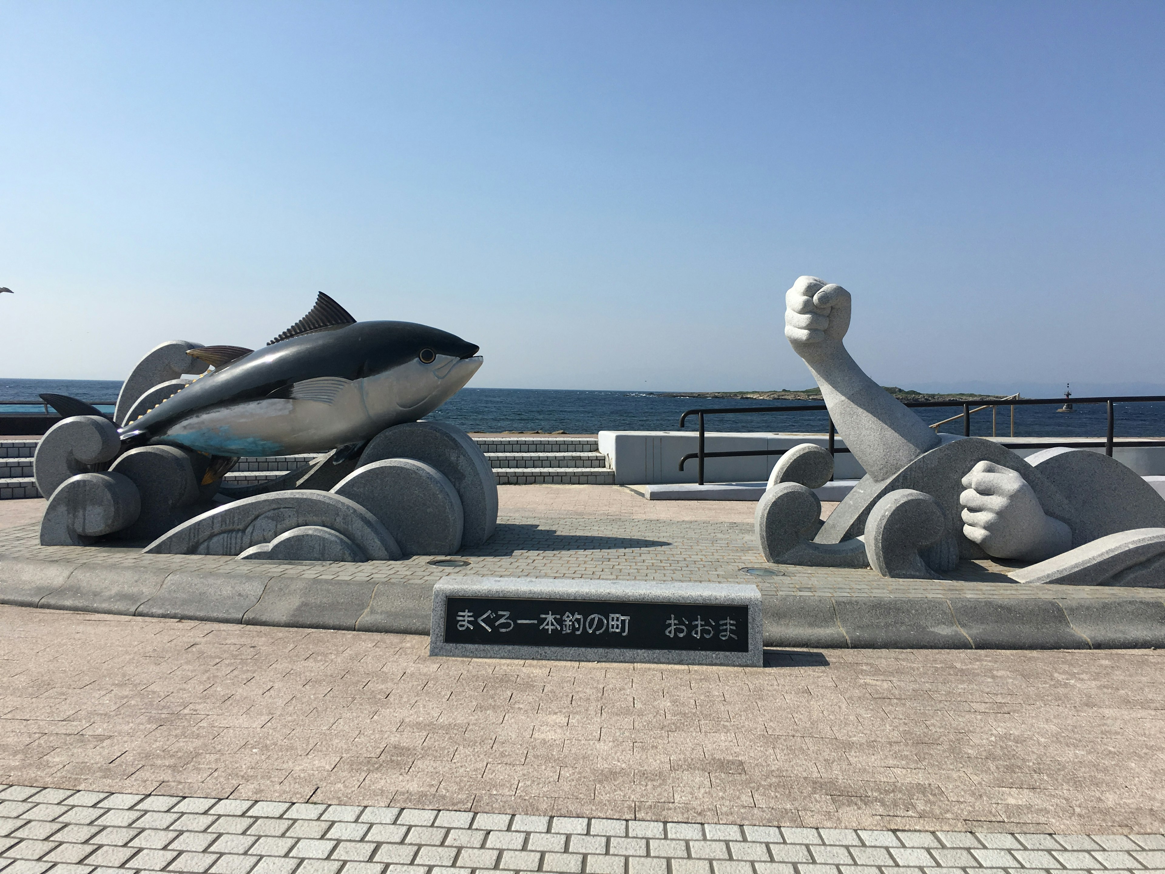 해변 산책로에 있는 돌고래와 인간 형상의 조각상