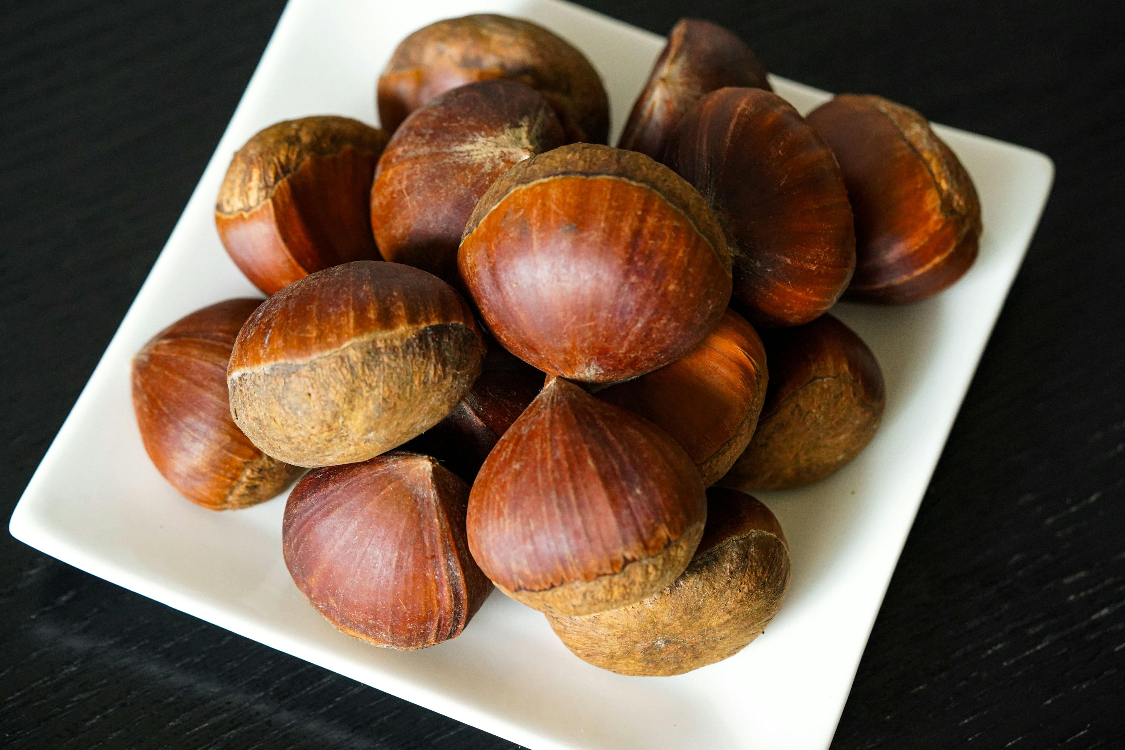 A pile of roasted chestnuts on a white plate