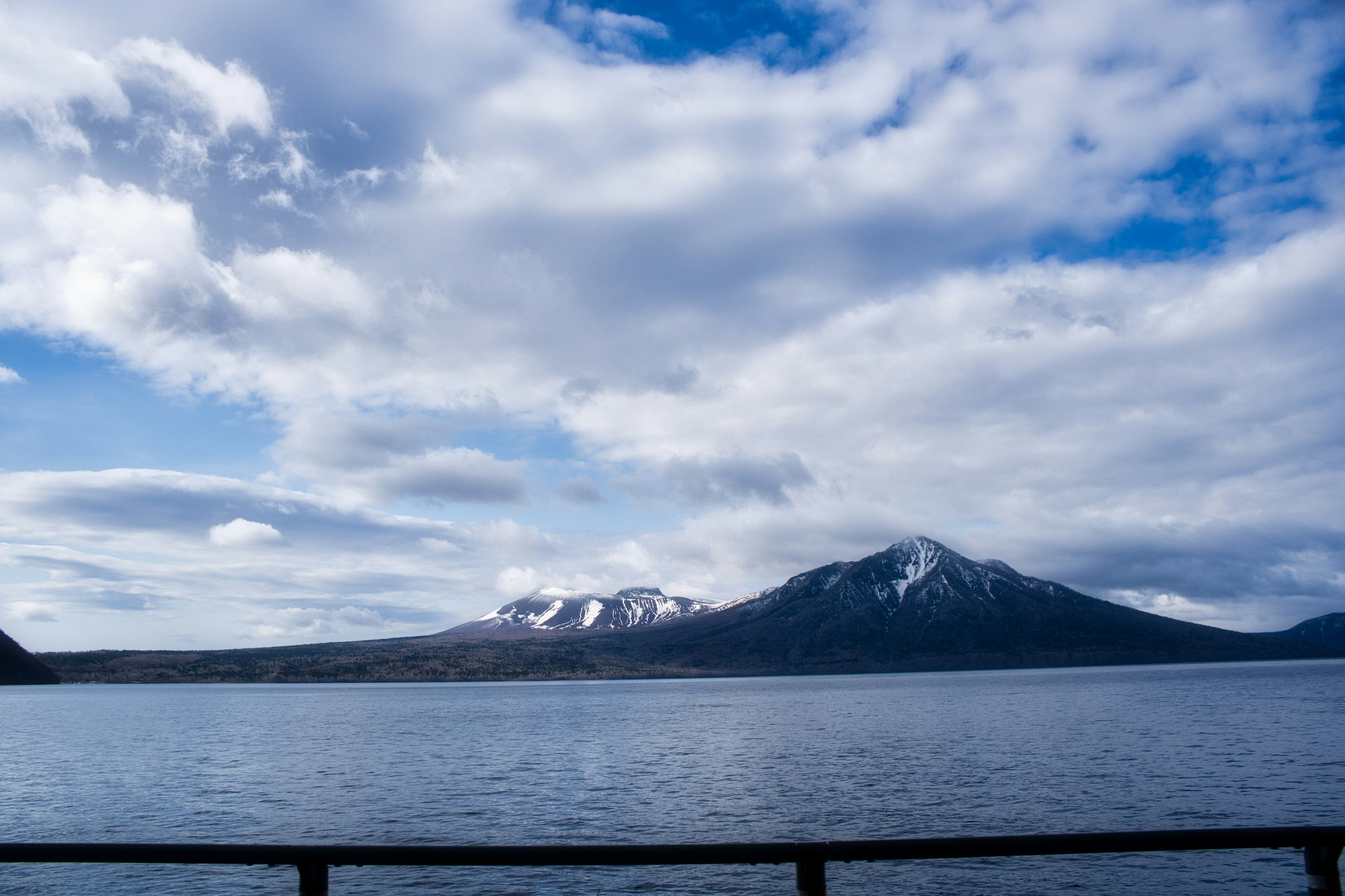 Vista escénica de montañas nevadas bajo un cielo azul sobre un lago