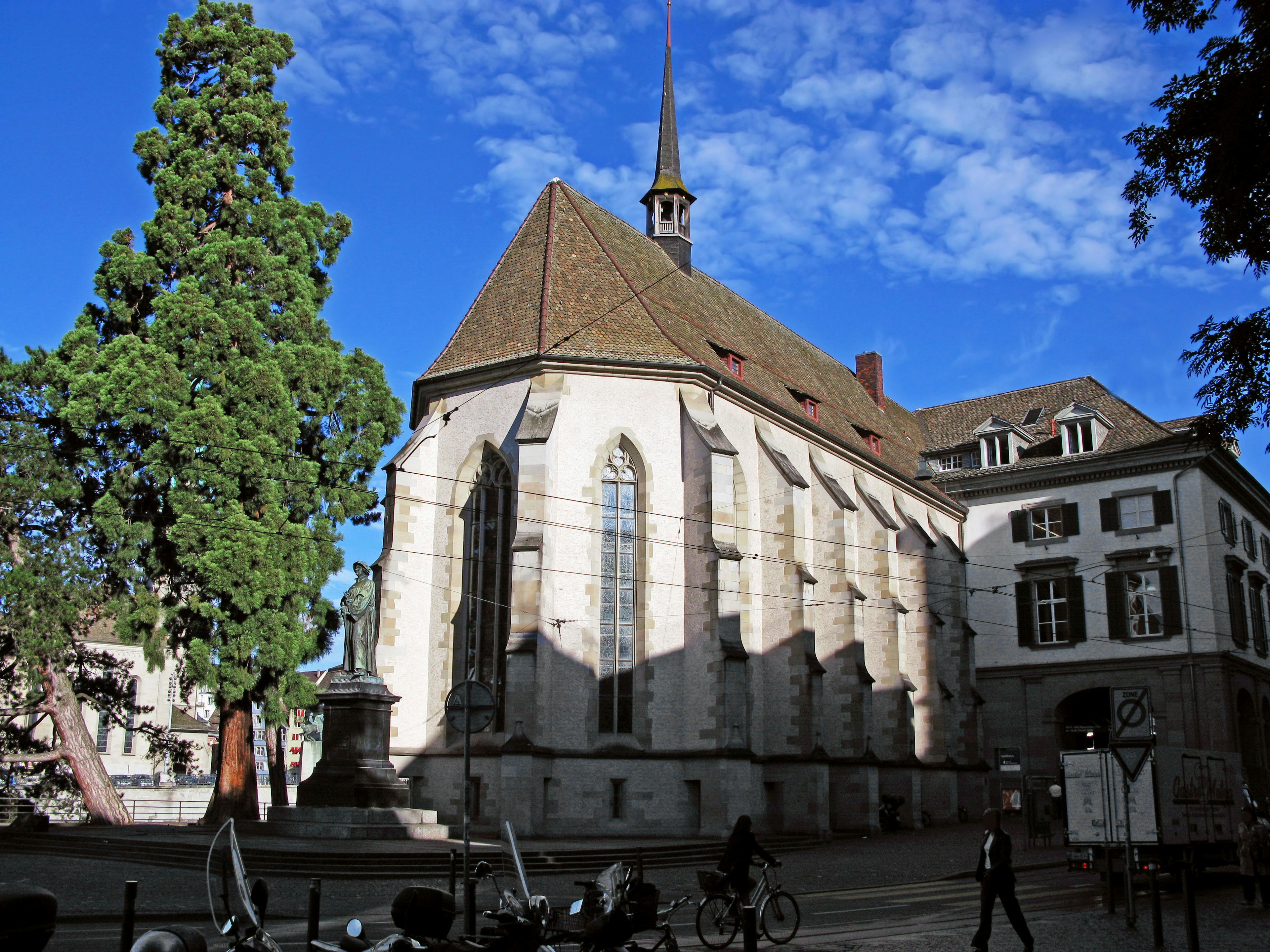 Historic church building under a blue sky with green trees and stone architecture