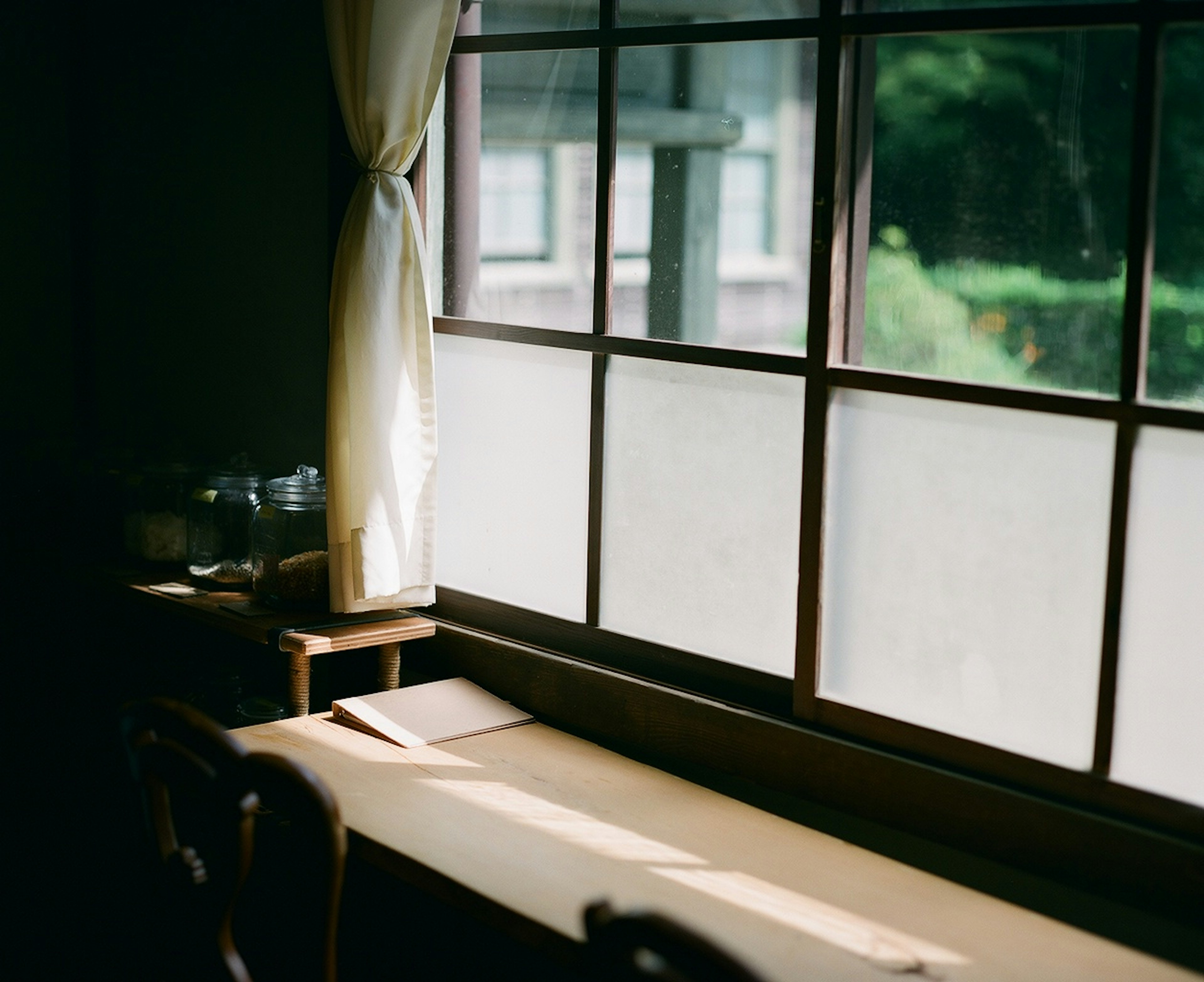 A serene room with a table by the window featuring glass containers and a white curtain