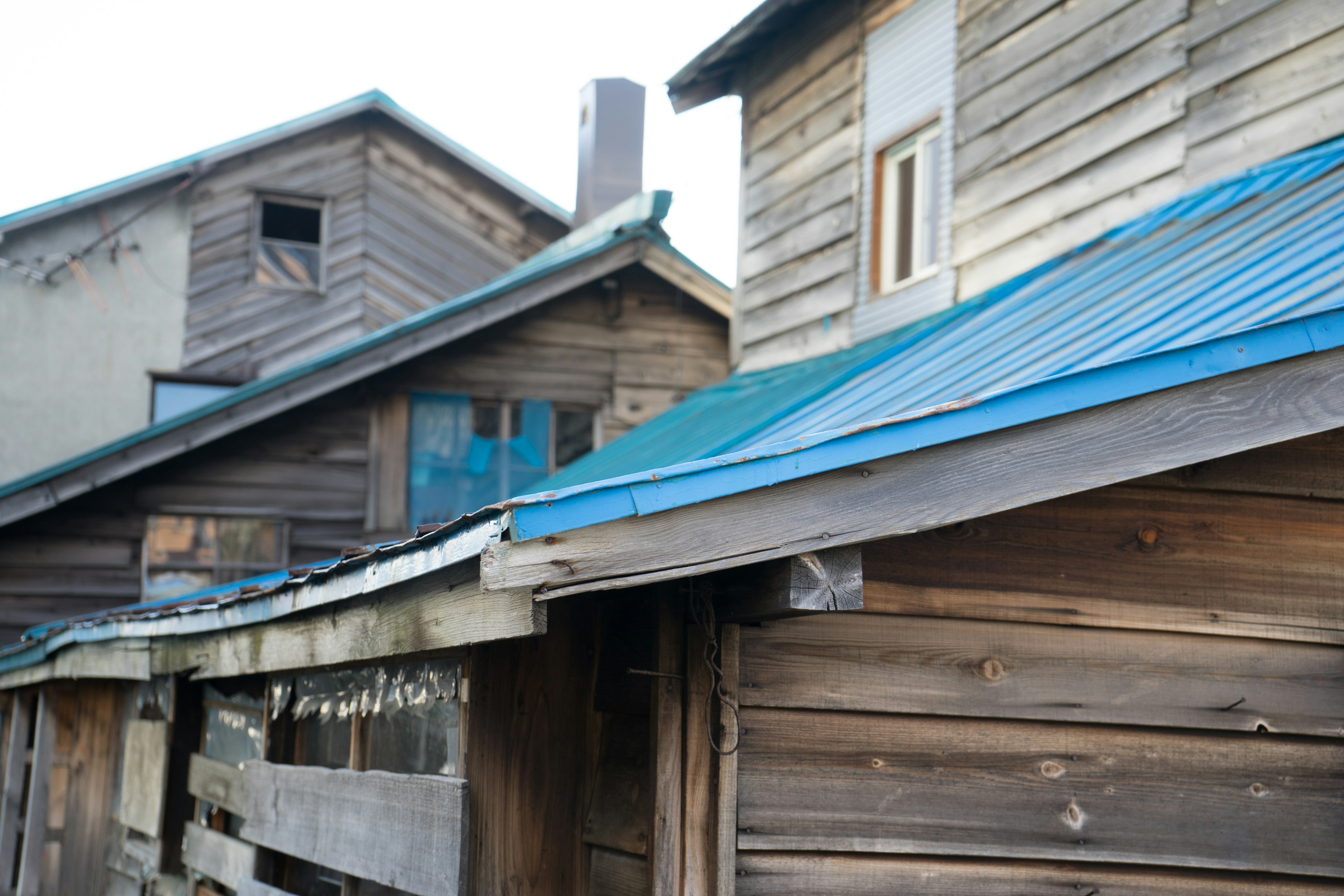 Außenansicht alter Holzhäuser mit blauem Dach und Holzfassade