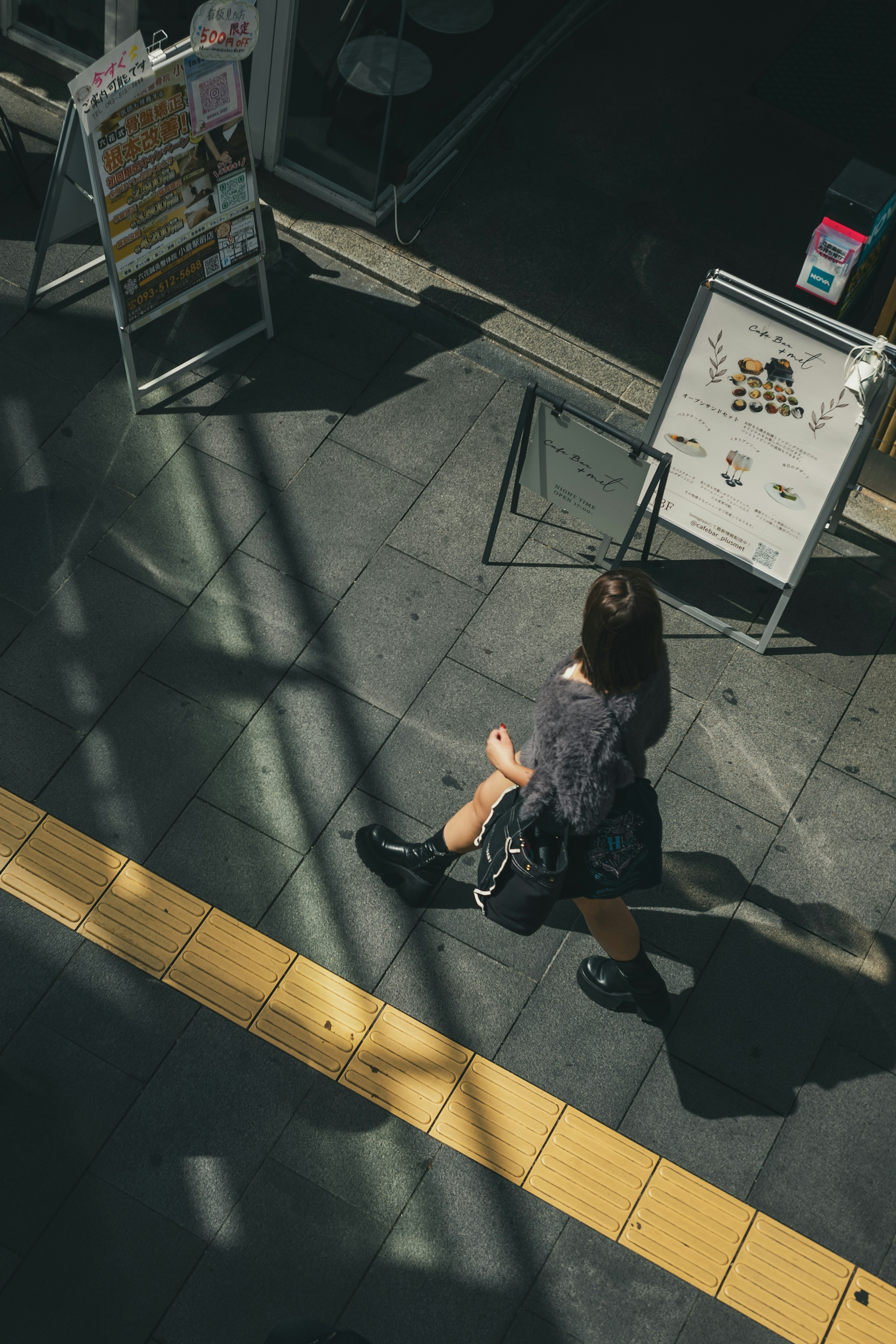 A woman walking on a train platform from an overhead perspective