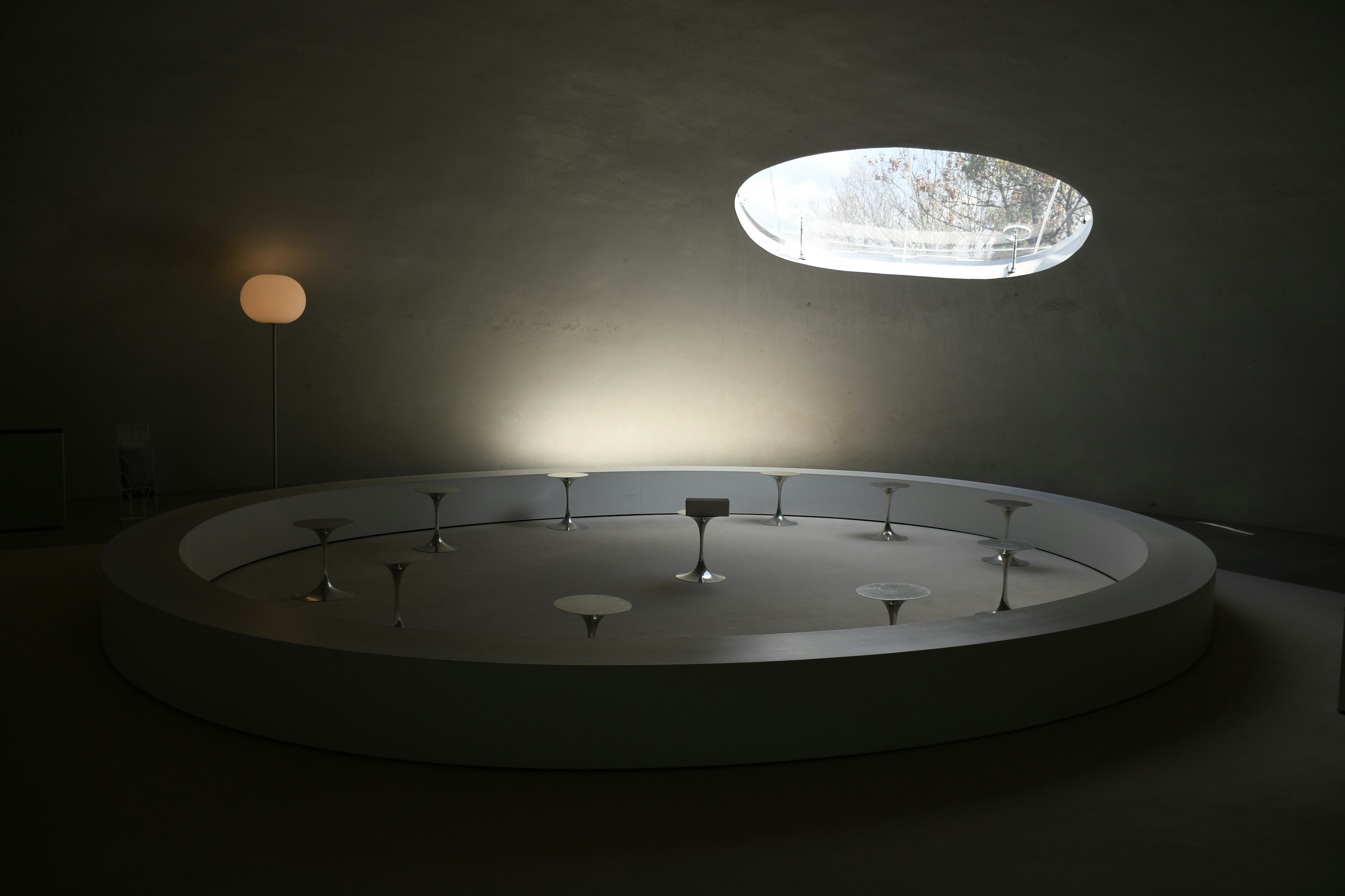 Minimalist interior featuring a round table and an oval window