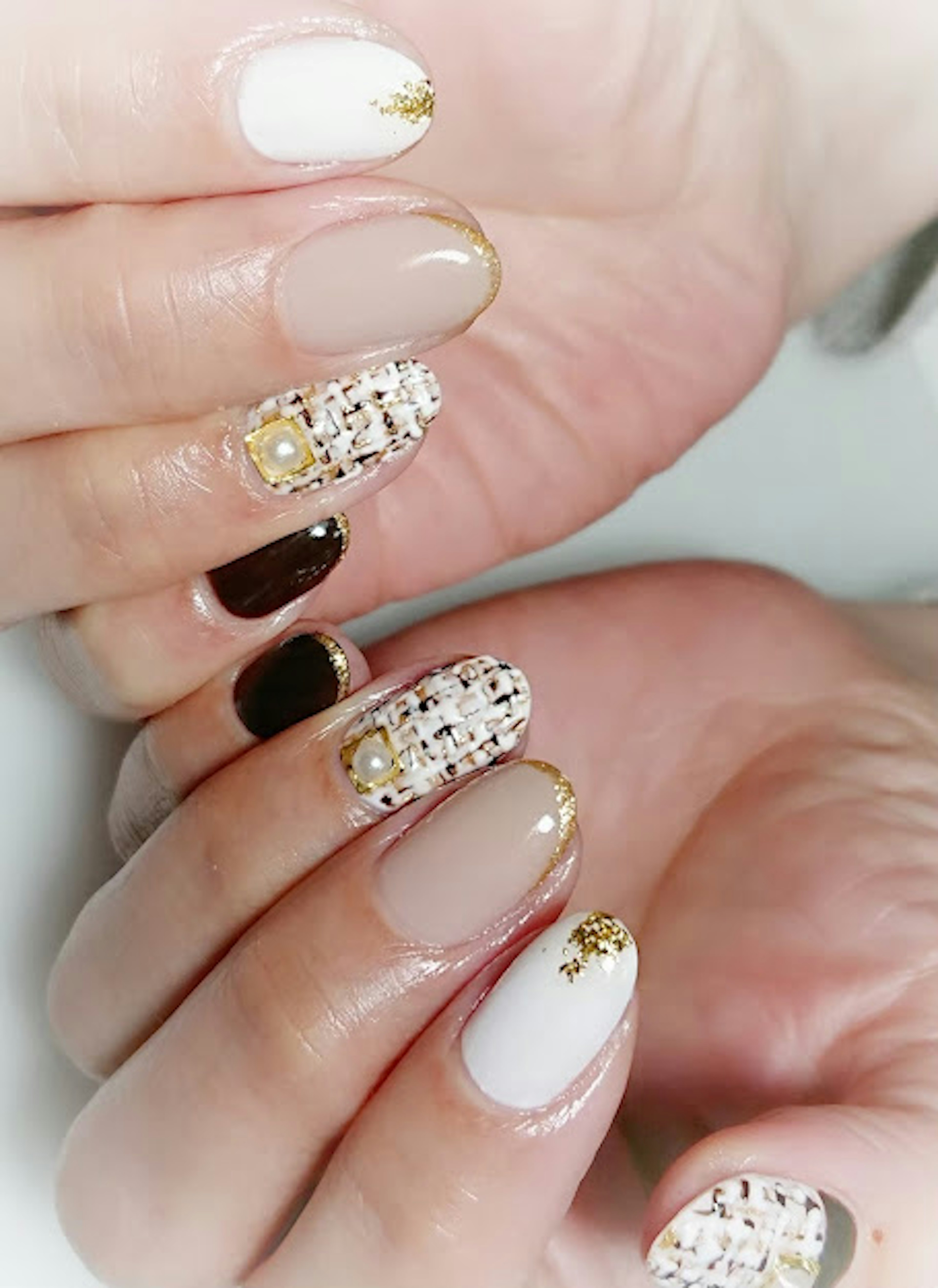 Ingrandimento di un design di nail art con mani che mostrano colori bianchi e beige con dettagli dorati