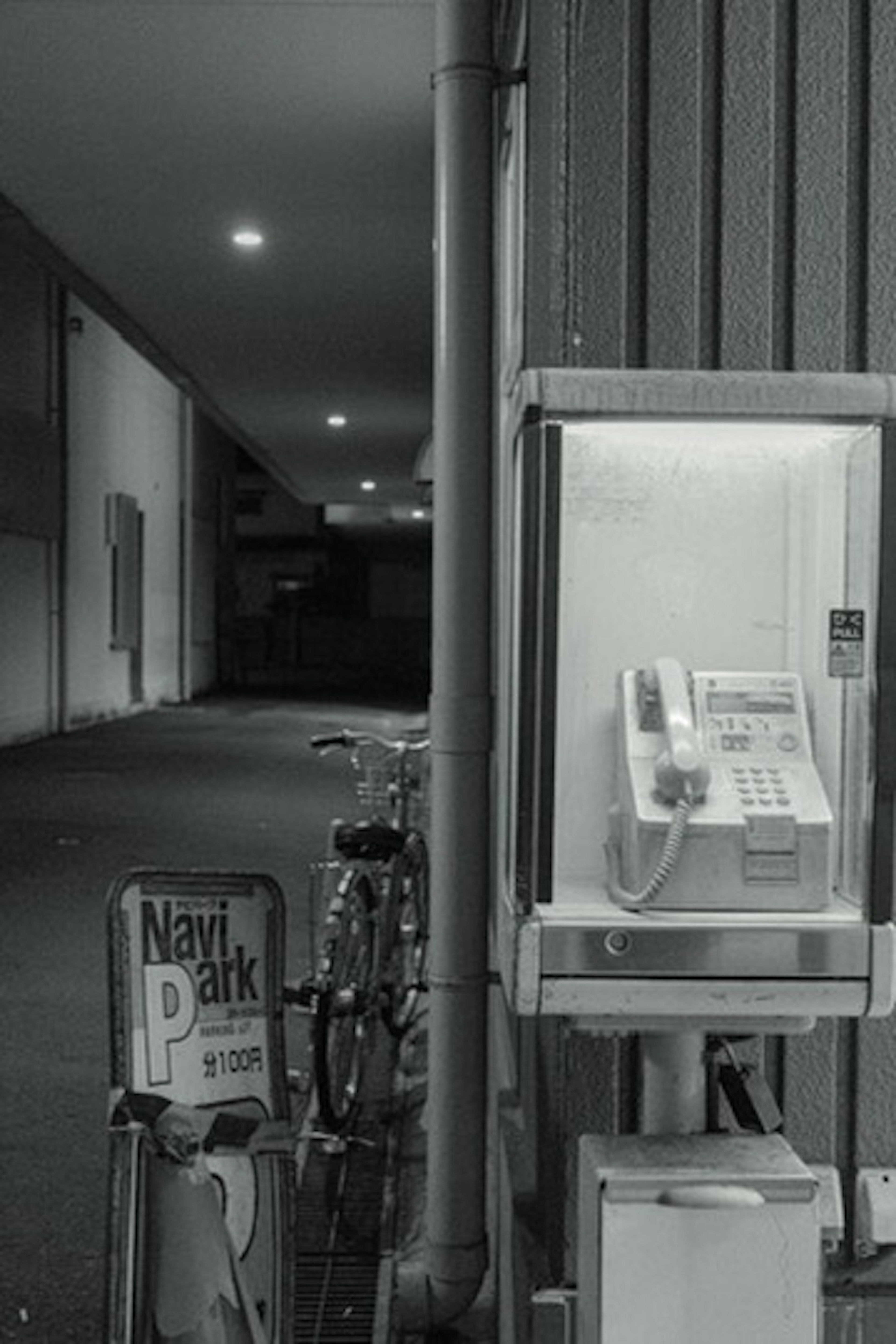 Imagen de una cabina telefónica y una bicicleta en un callejón oscuro