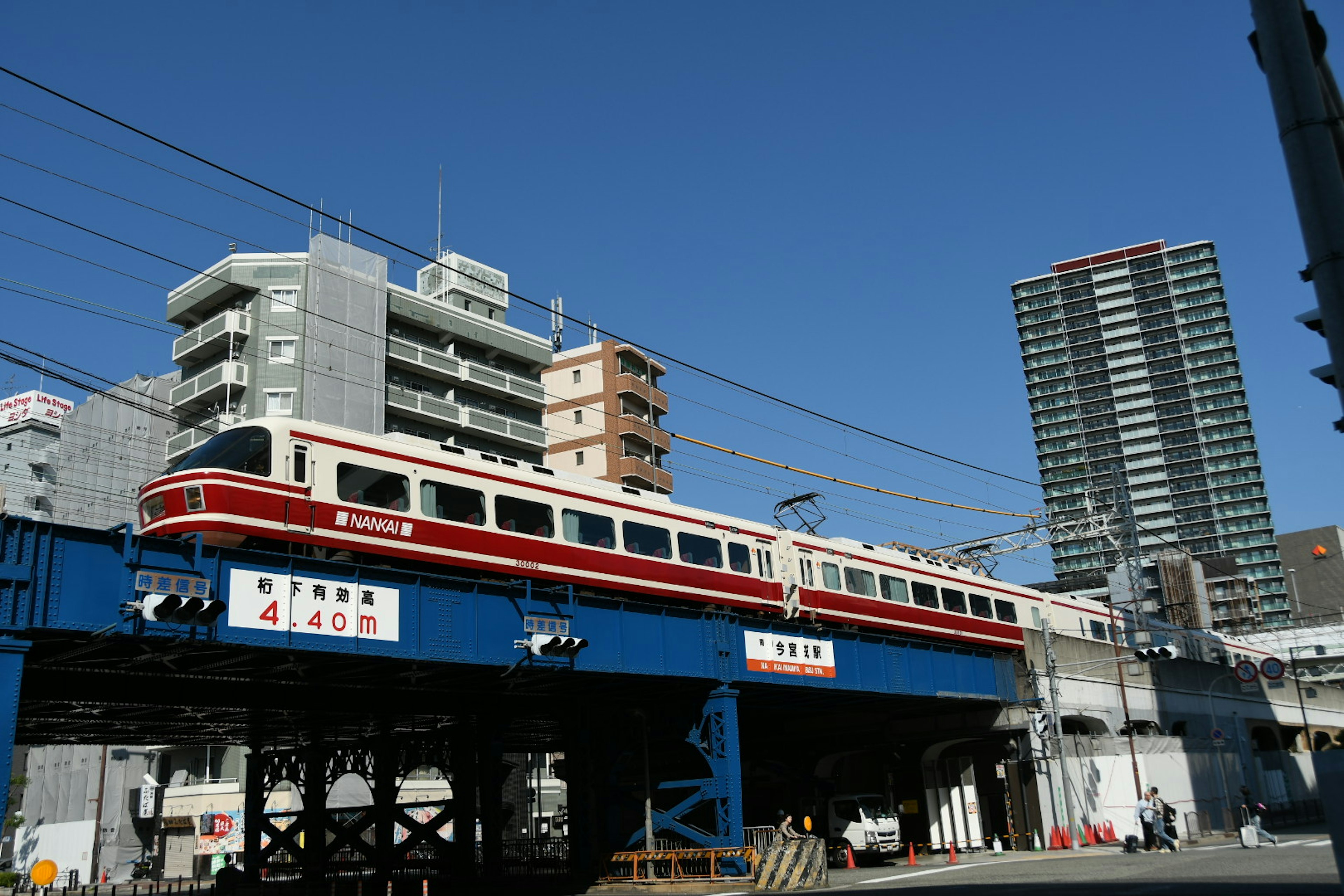 在蓝天背景下，红色火车在城市环境中的高架轨道上行驶