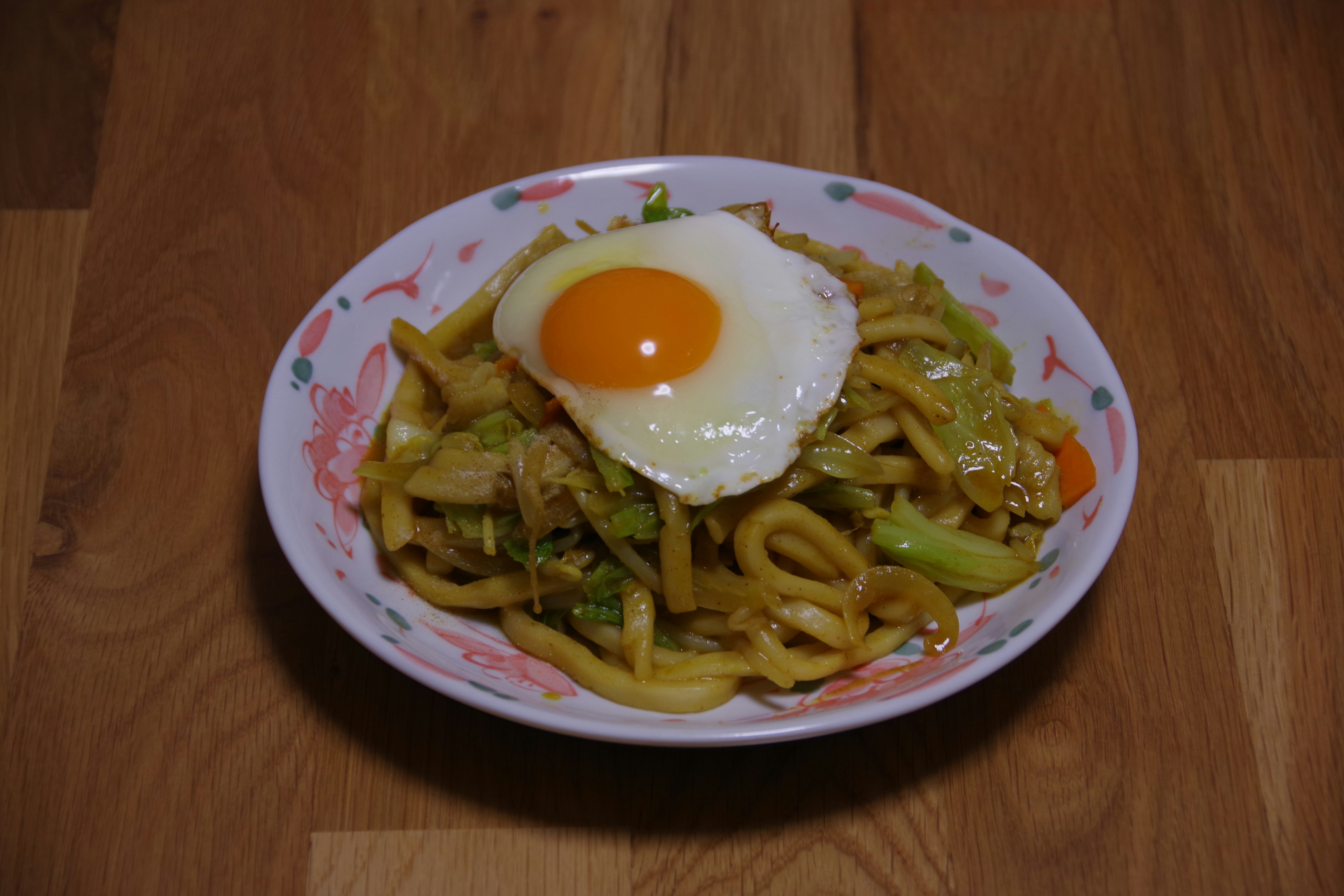 Piatto di noodles udon saltati con un uovo fritto sopra