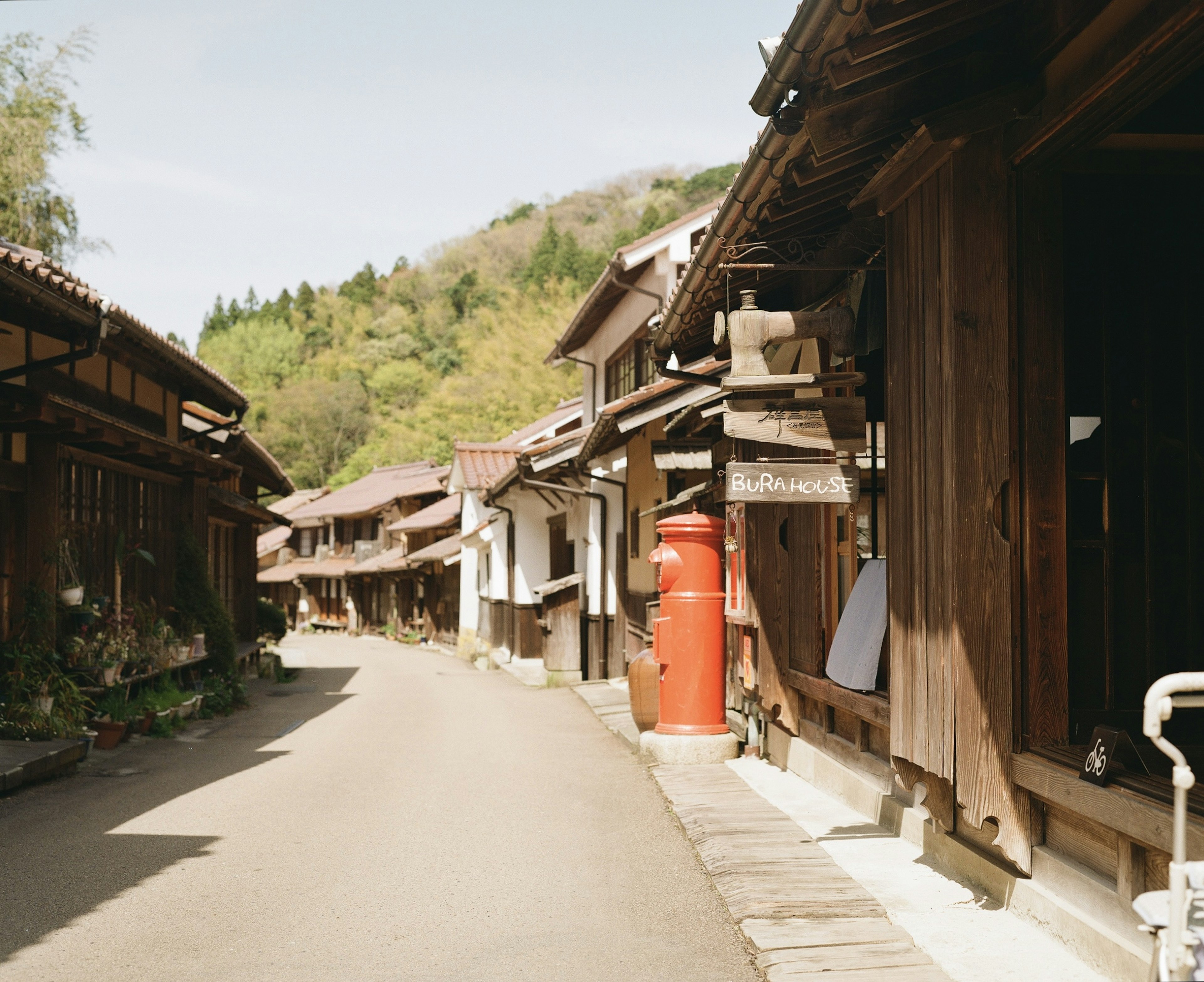 古い木造の家々が並ぶ静かな通り 緑の山々が背景にある