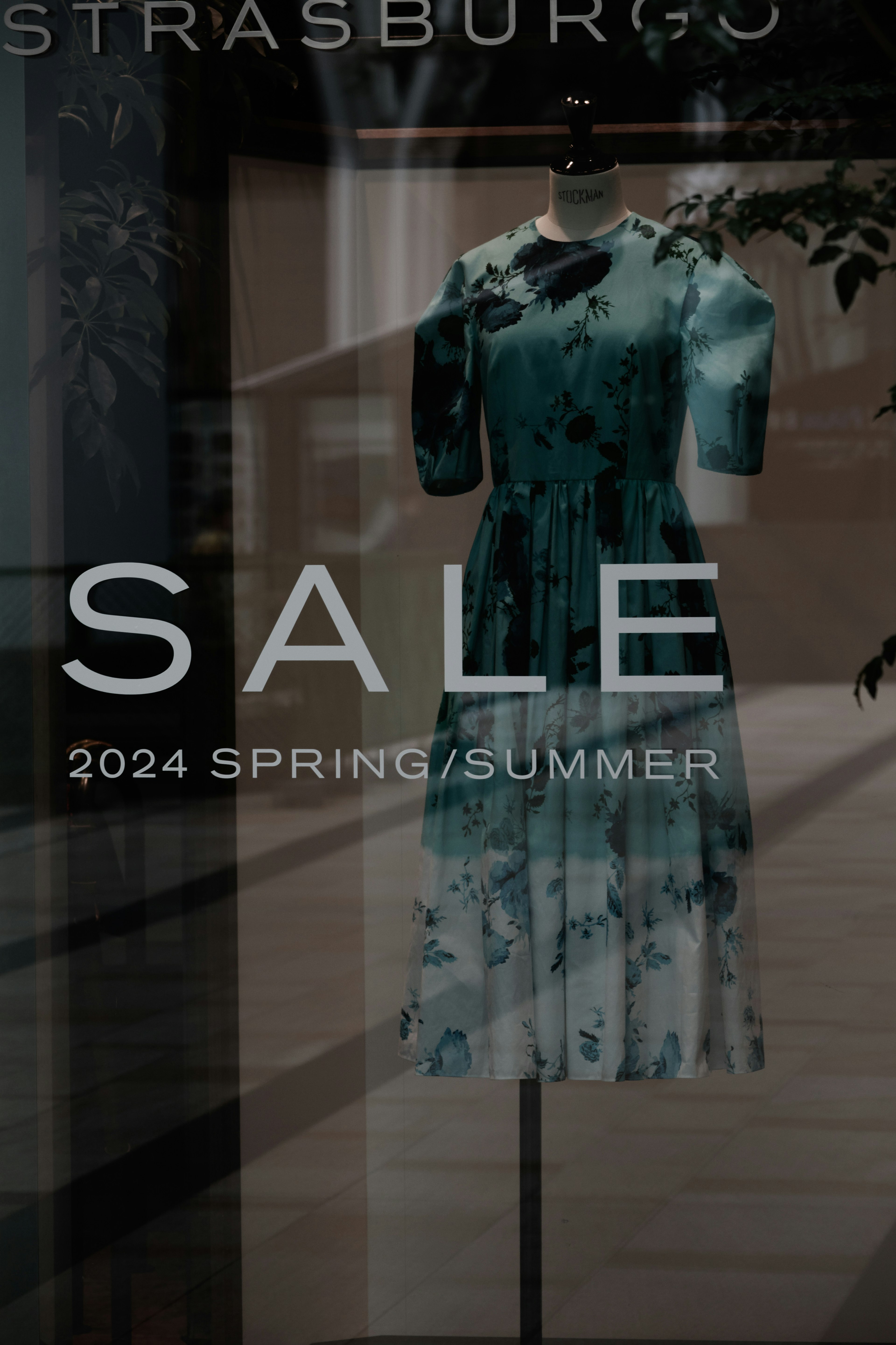 Display window featuring a blue floral dress Sale sign and 2024 Spring/Summer collection