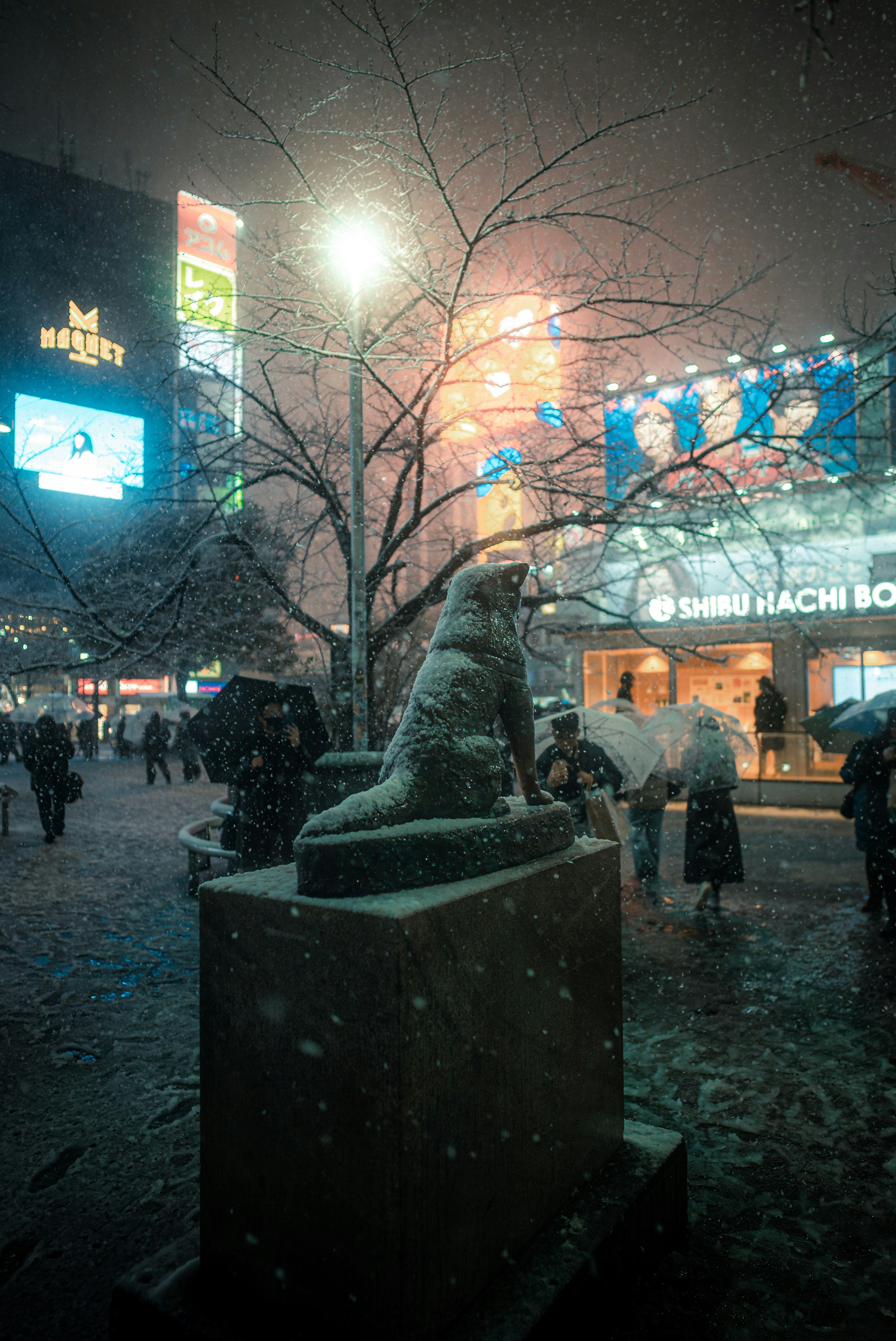 雪中狗的雕像和周围的人们