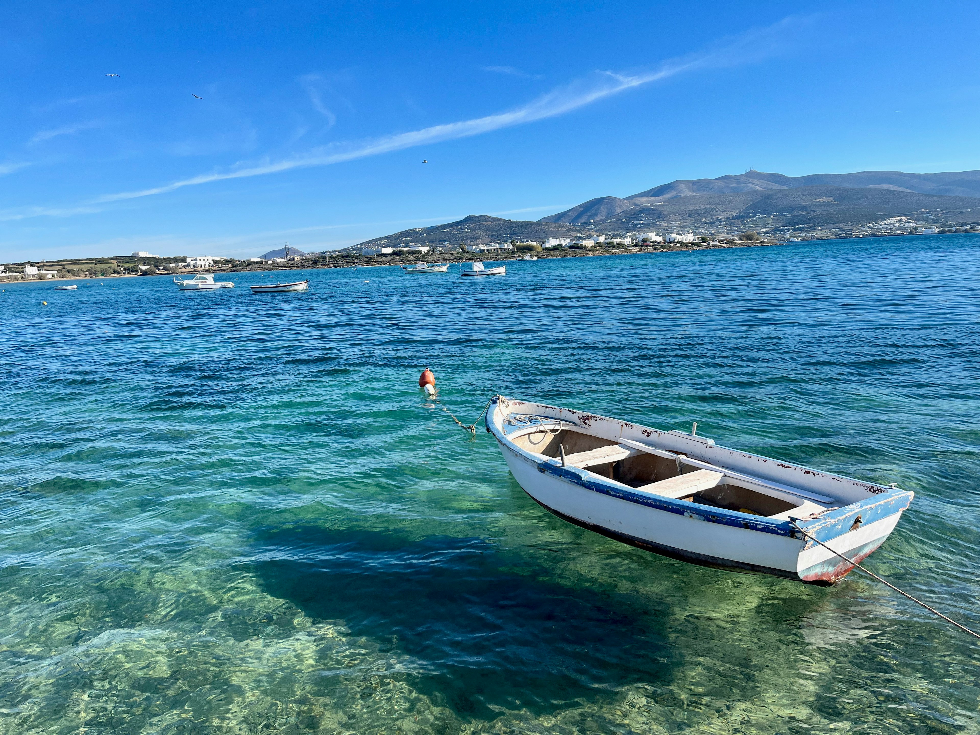 Kleine Boot, das in klarem blauem Wasser mit Bergen im Hintergrund schwimmt