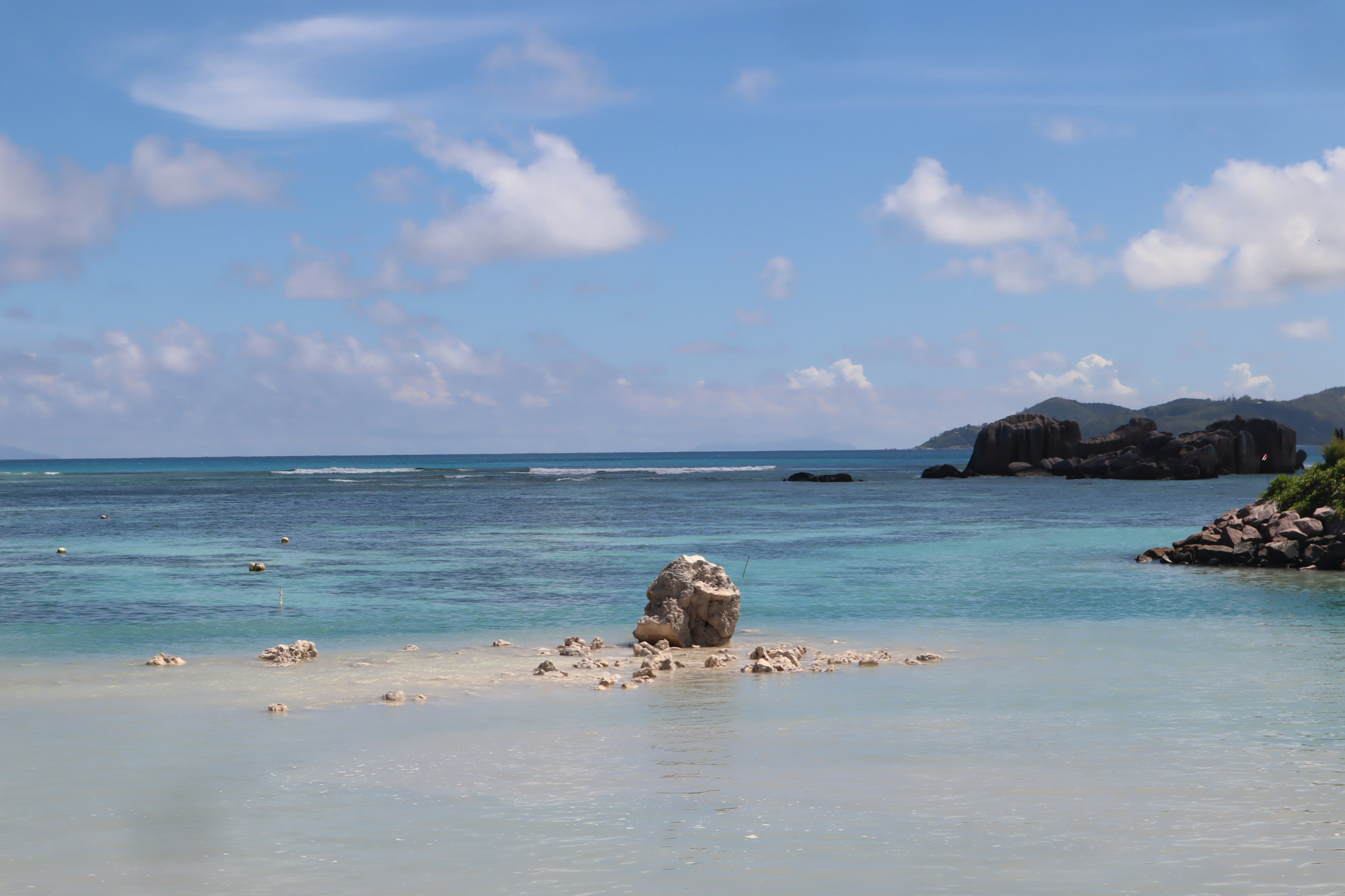 Une vue panoramique de l'océan bleu et de la plage de sable blanc avec un rocher solitaire