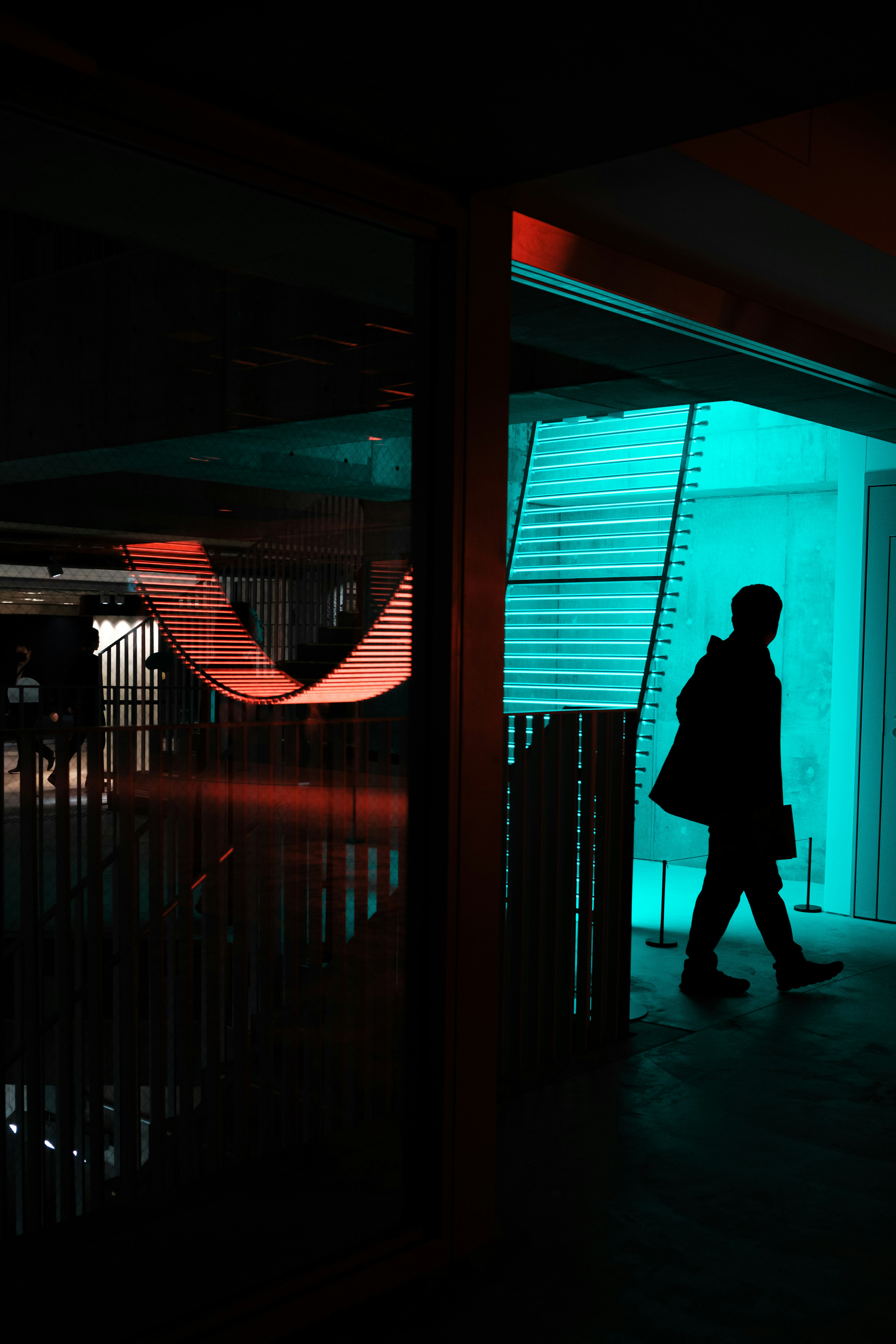 Silhouette of a person walking under blue and red lighting