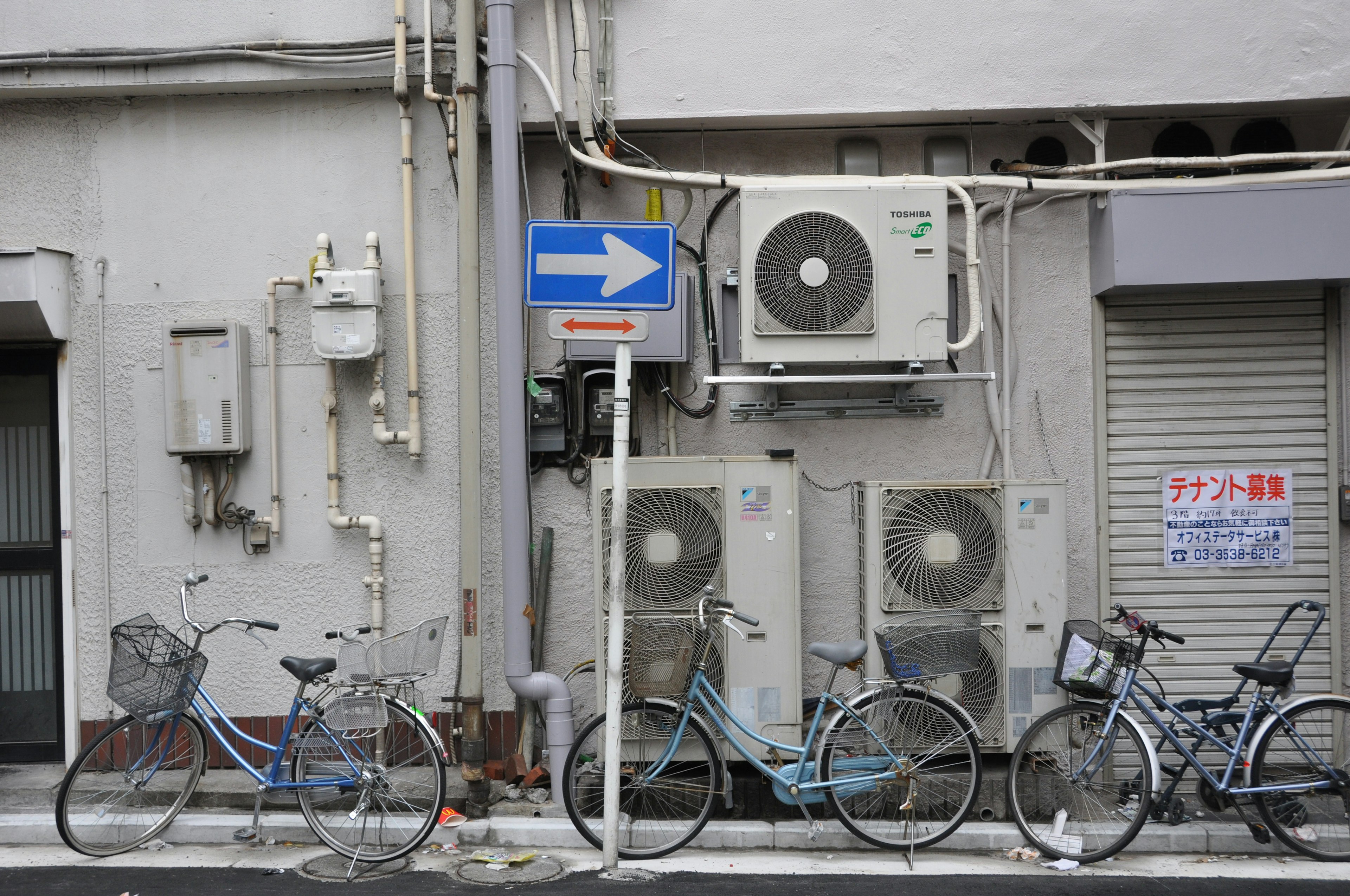 Urban scene featuring mounted air conditioning units and parked blue bicycles