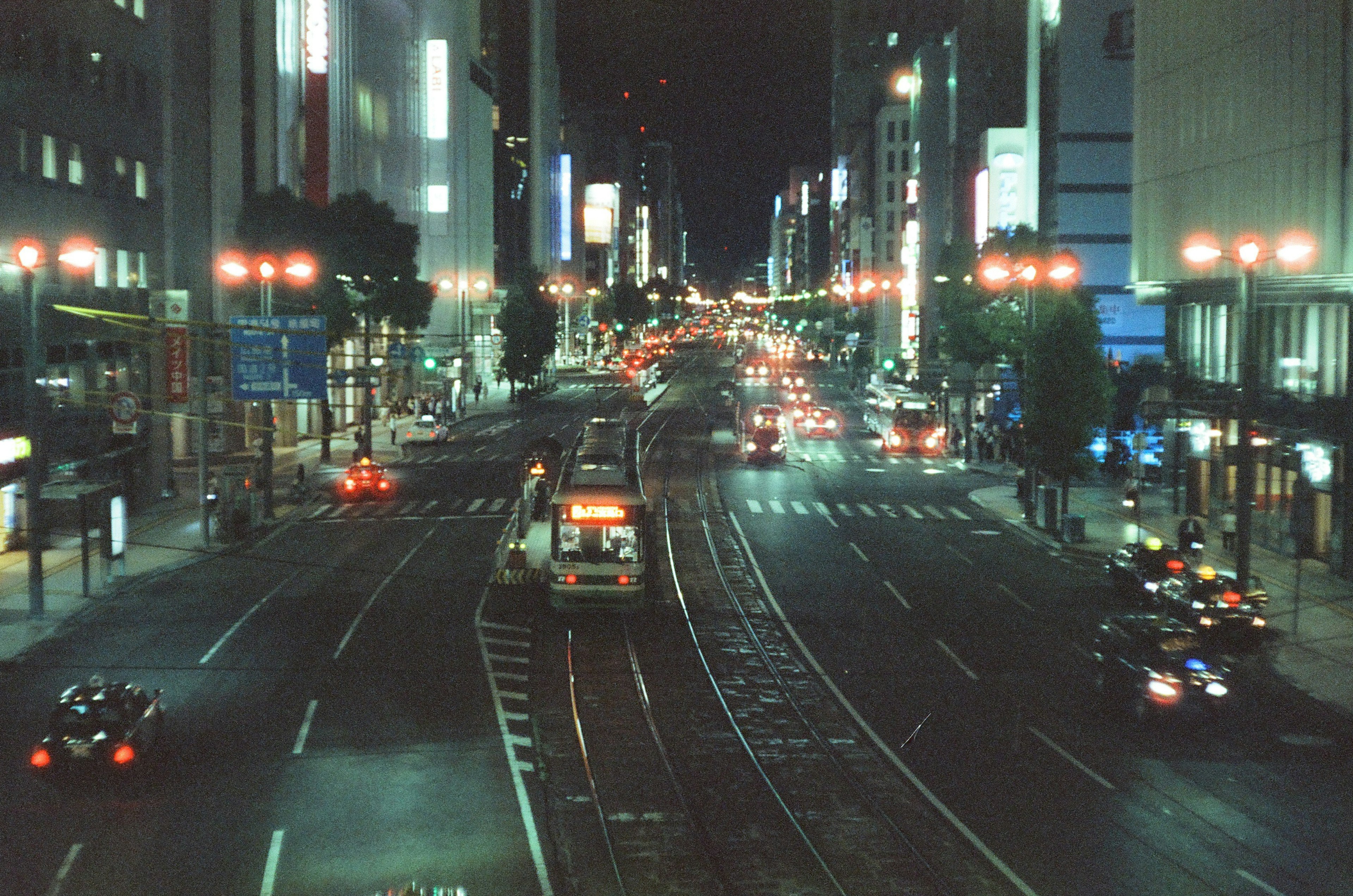 夜の都市の通りに並ぶ車両とネオンの光