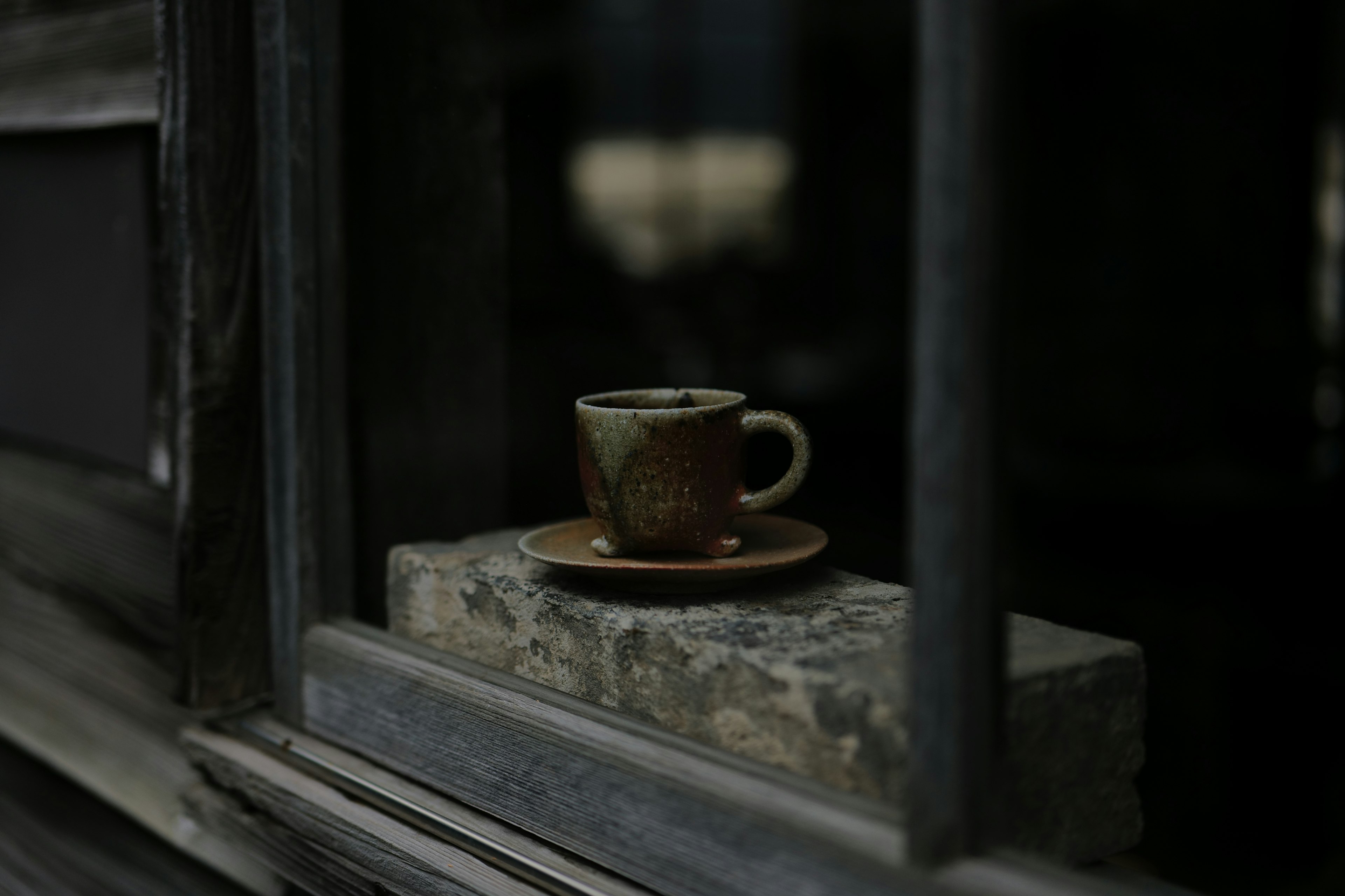 A quiet scene featuring a brown cup and saucer seen through a window