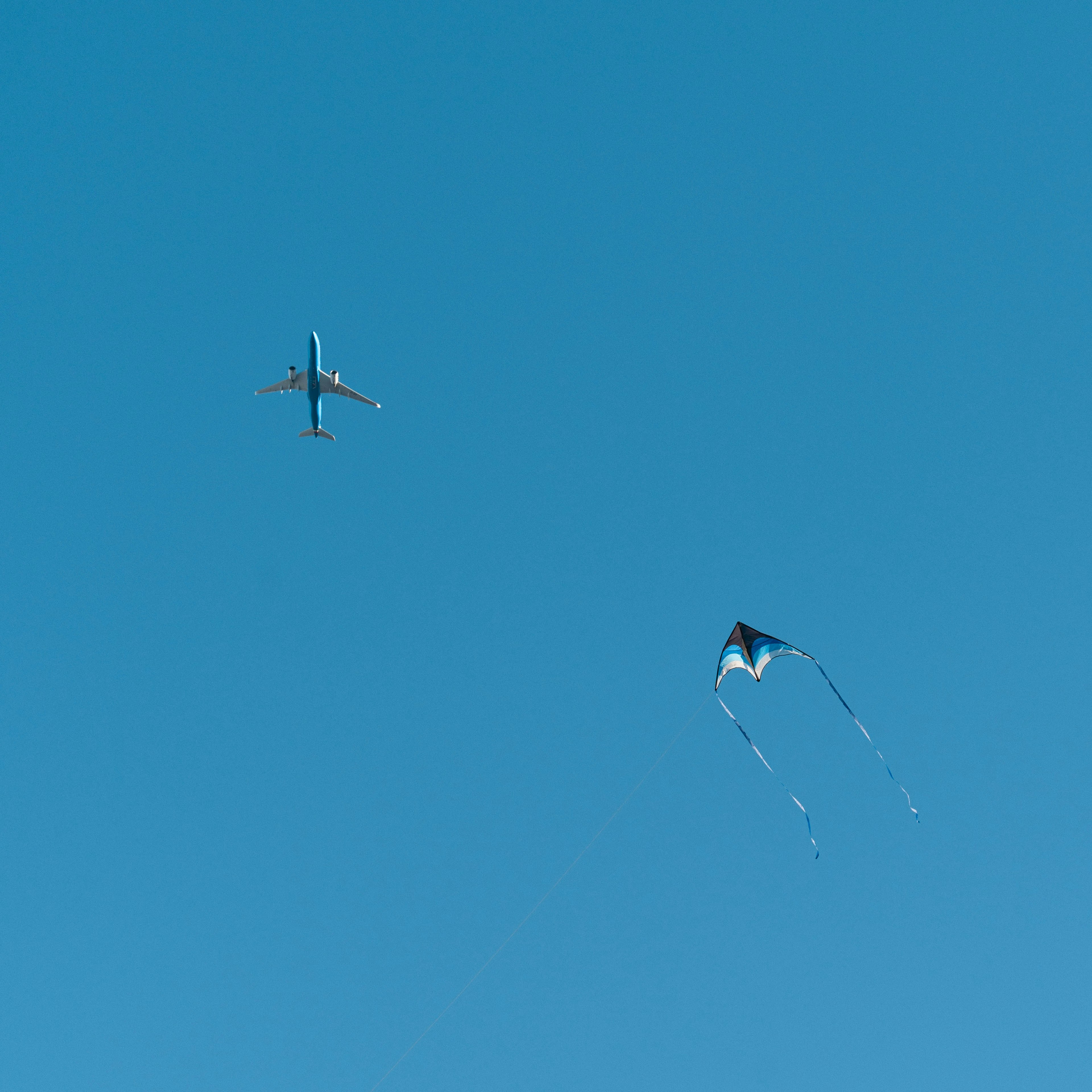 Flugzeug und Drachen fliegen in einem blauen Himmel