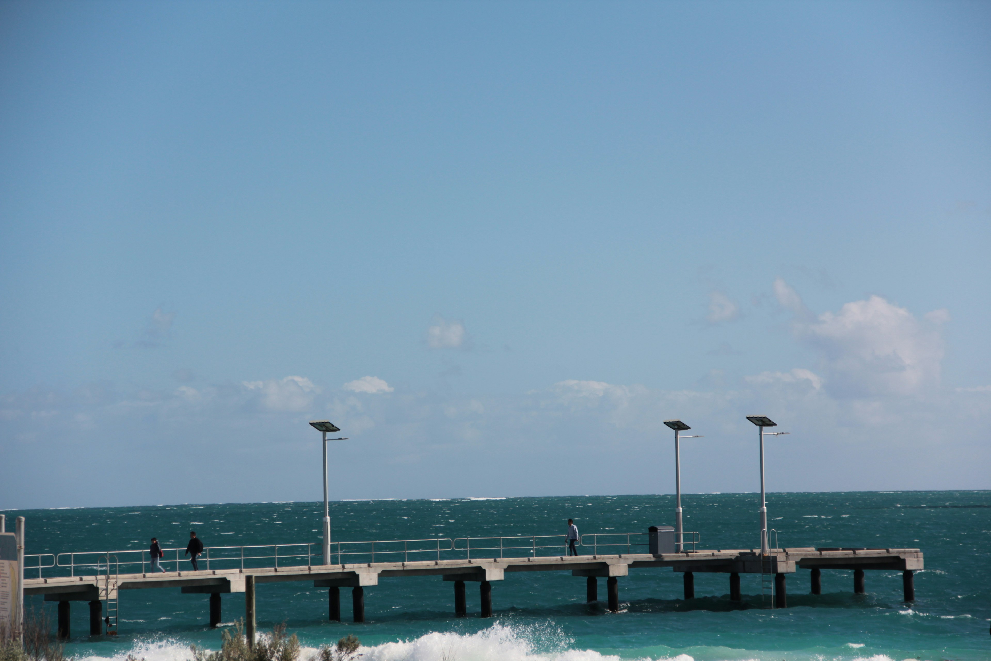 青い海と空の背景にある桟橋と波