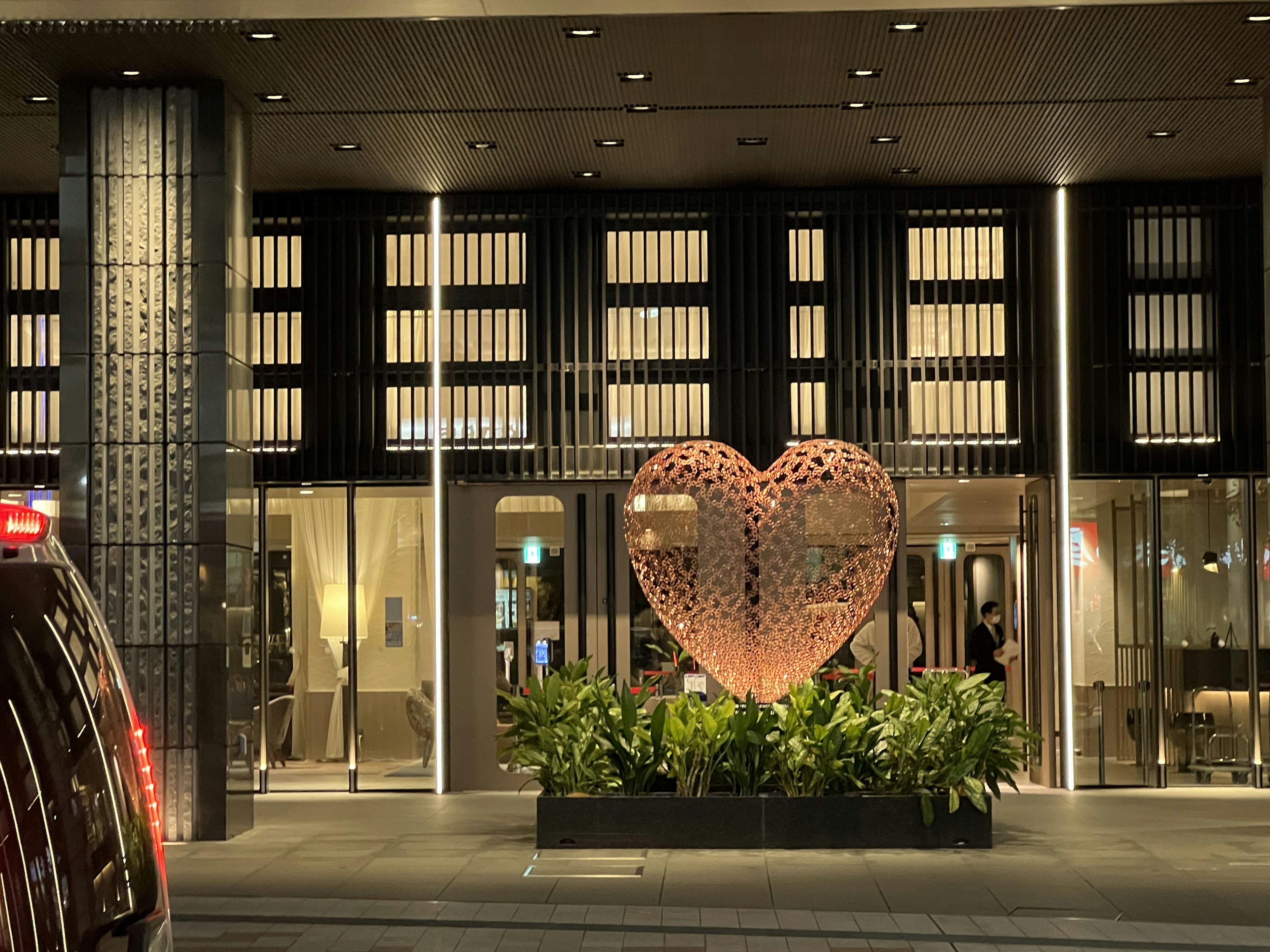 Gran escultura en forma de corazón en la entrada de un hotel moderno rodeada de vegetación