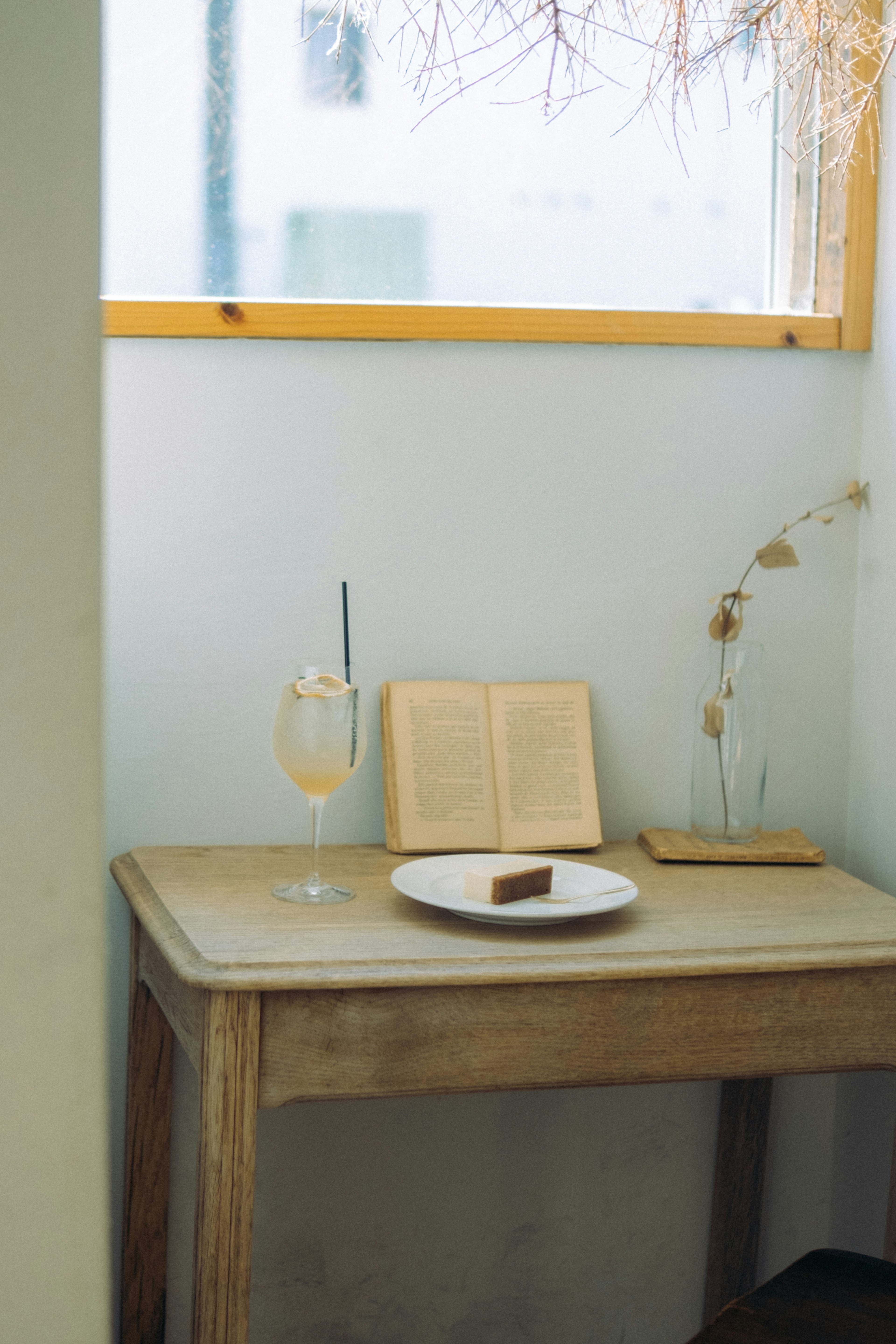 A serene corner with a wooden table featuring a drink and cake