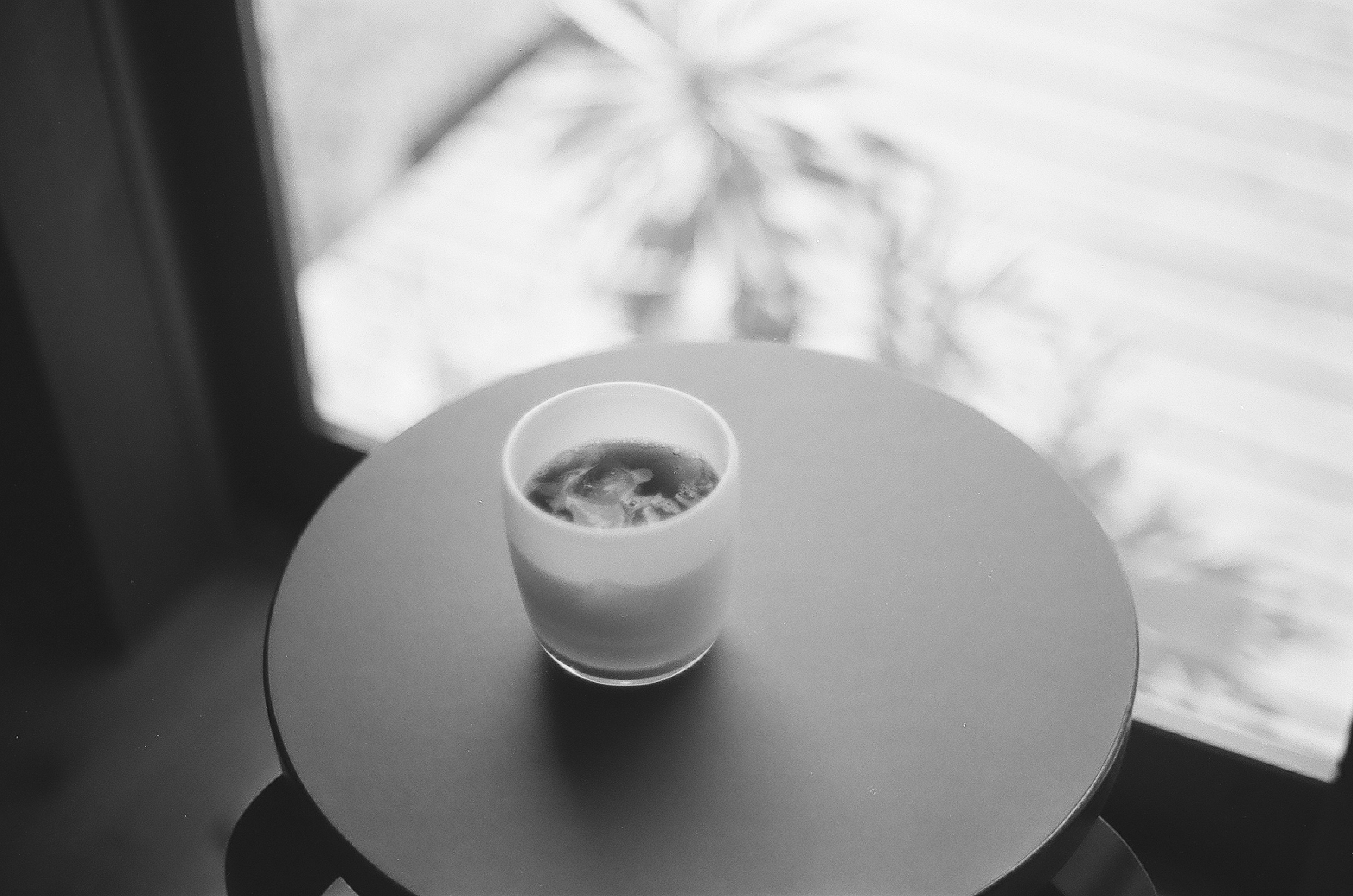 Black and white photo of a cup on a table with a drink inside