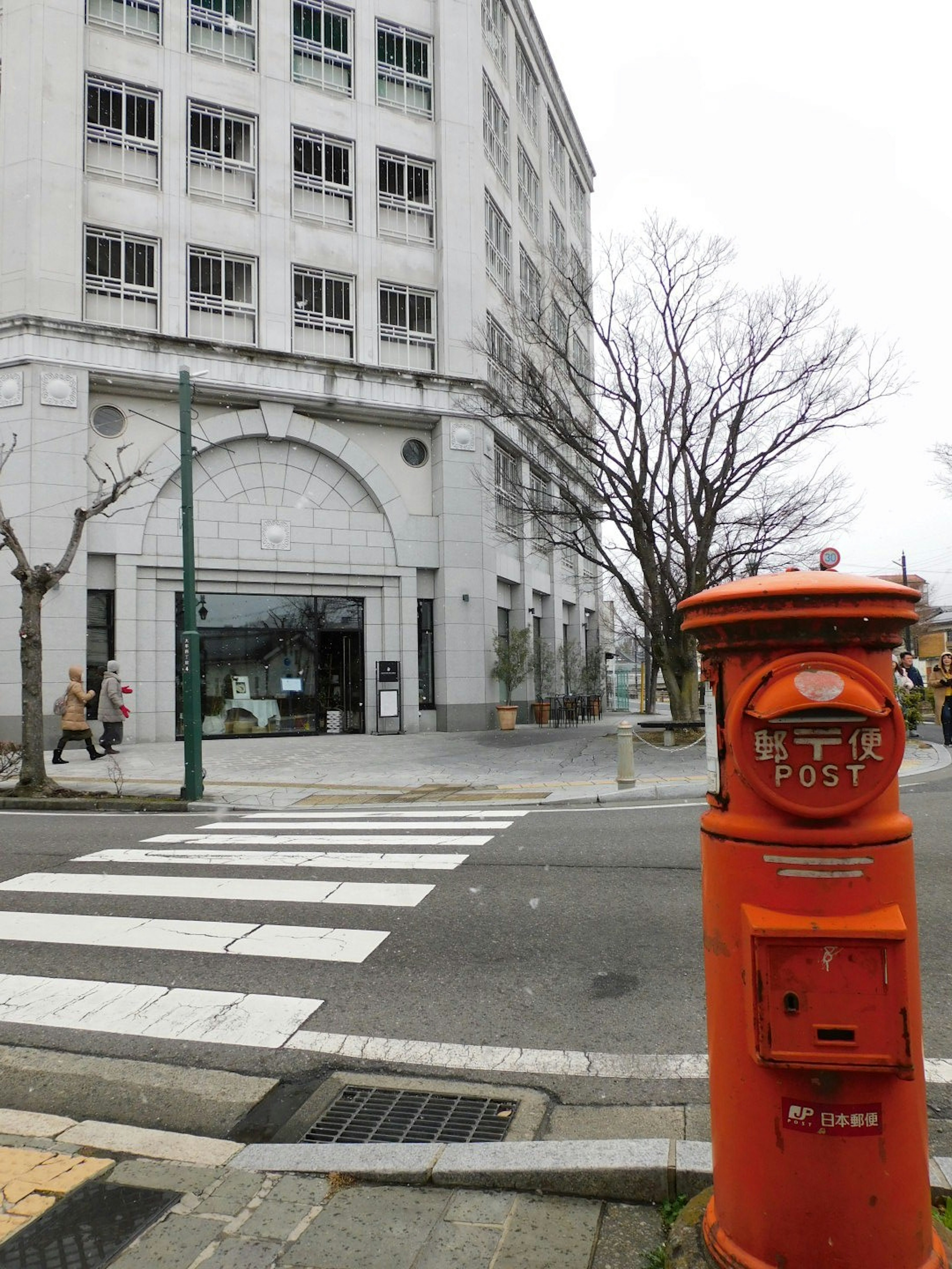 Scena di strada con una cassetta postale rossa e un edificio moderno