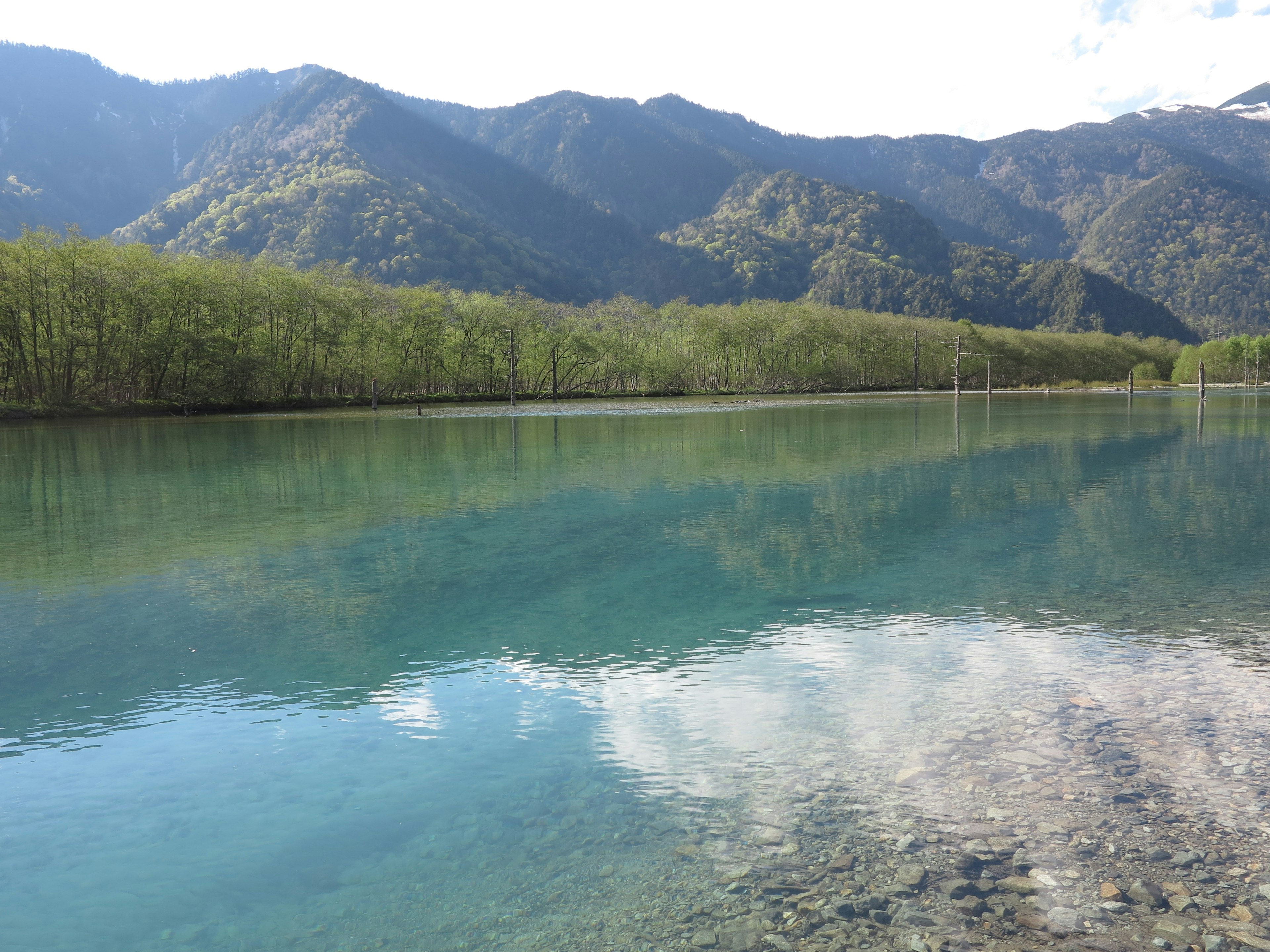 Un lago azul sereno que refleja montañas y vegetación circundante