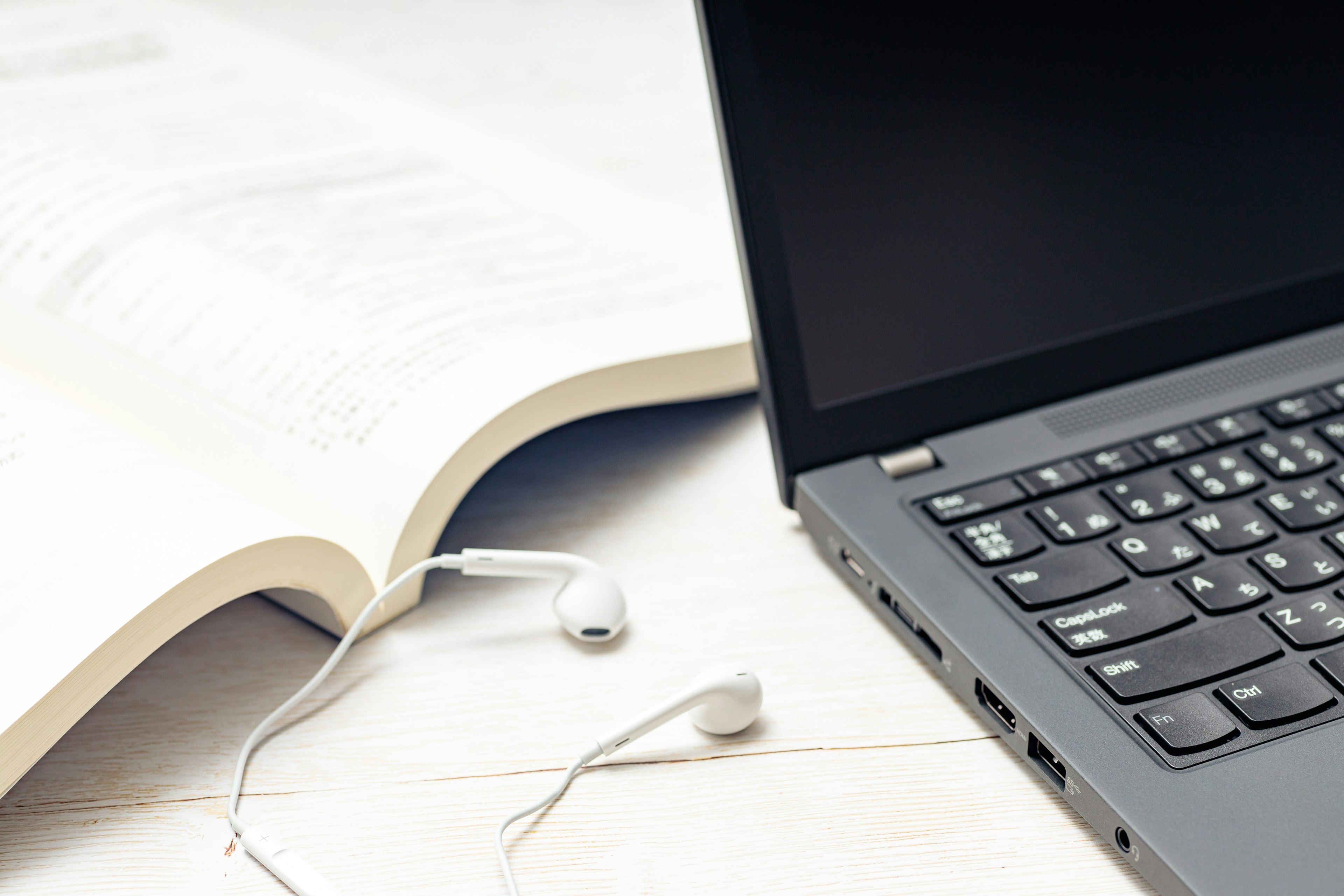 A laptop and an open textbook on a desk